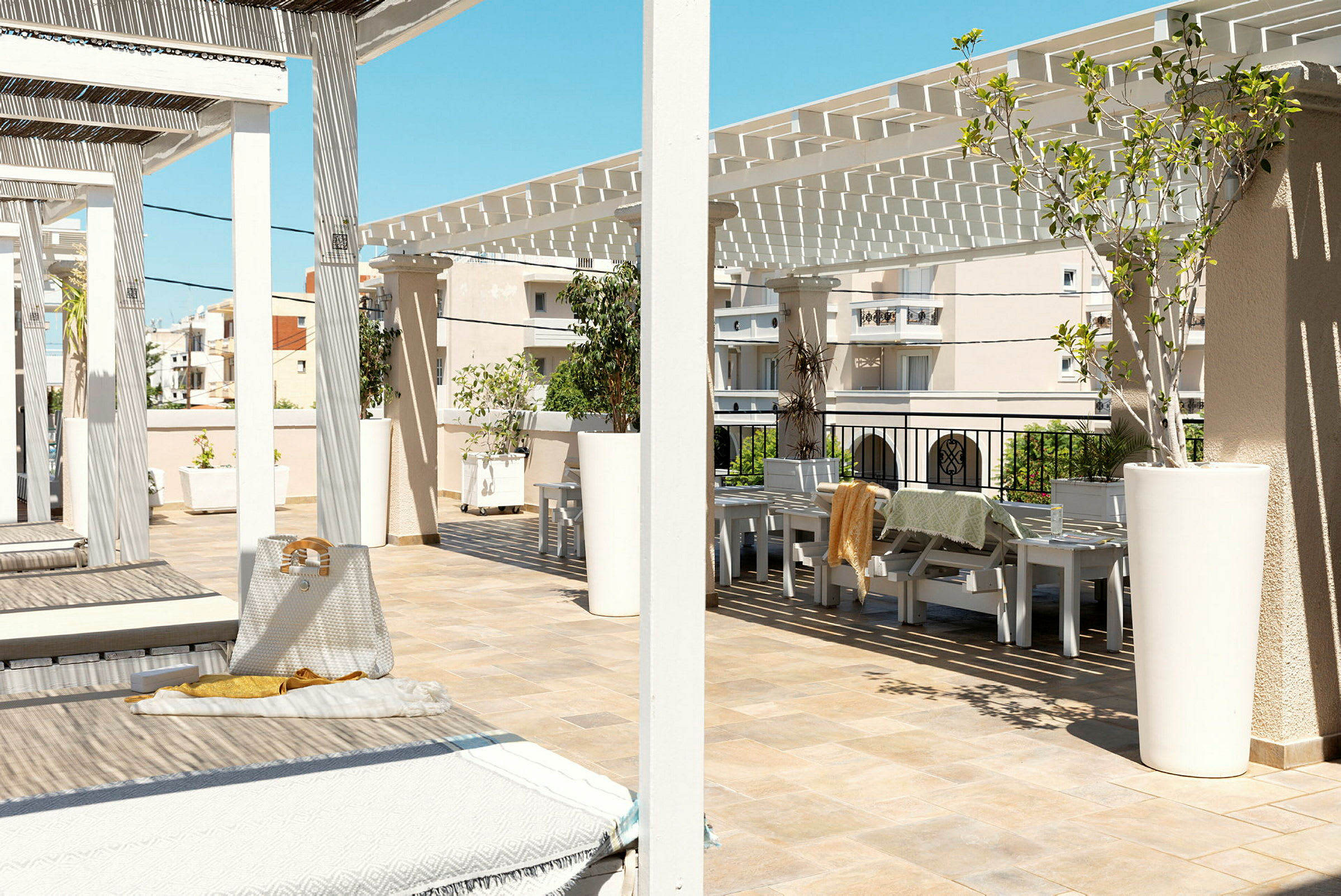 Solrik terrasse med solsenger og sitteplasser under en hvit pergola. (AI-generert tekst)