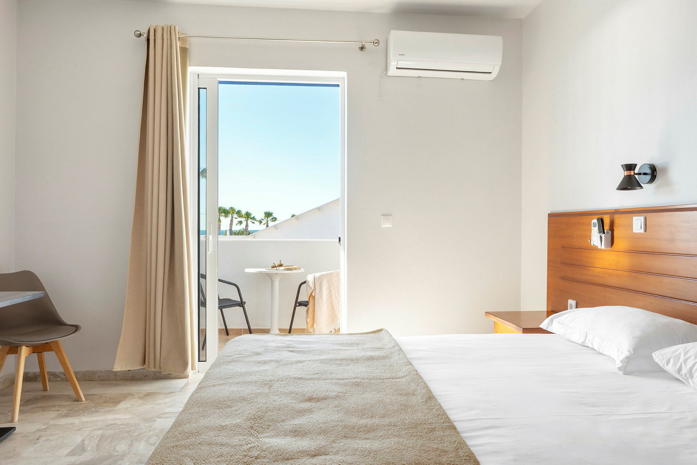 Inne på et hotellrom med seng og balkong. (AI-generert tekst)