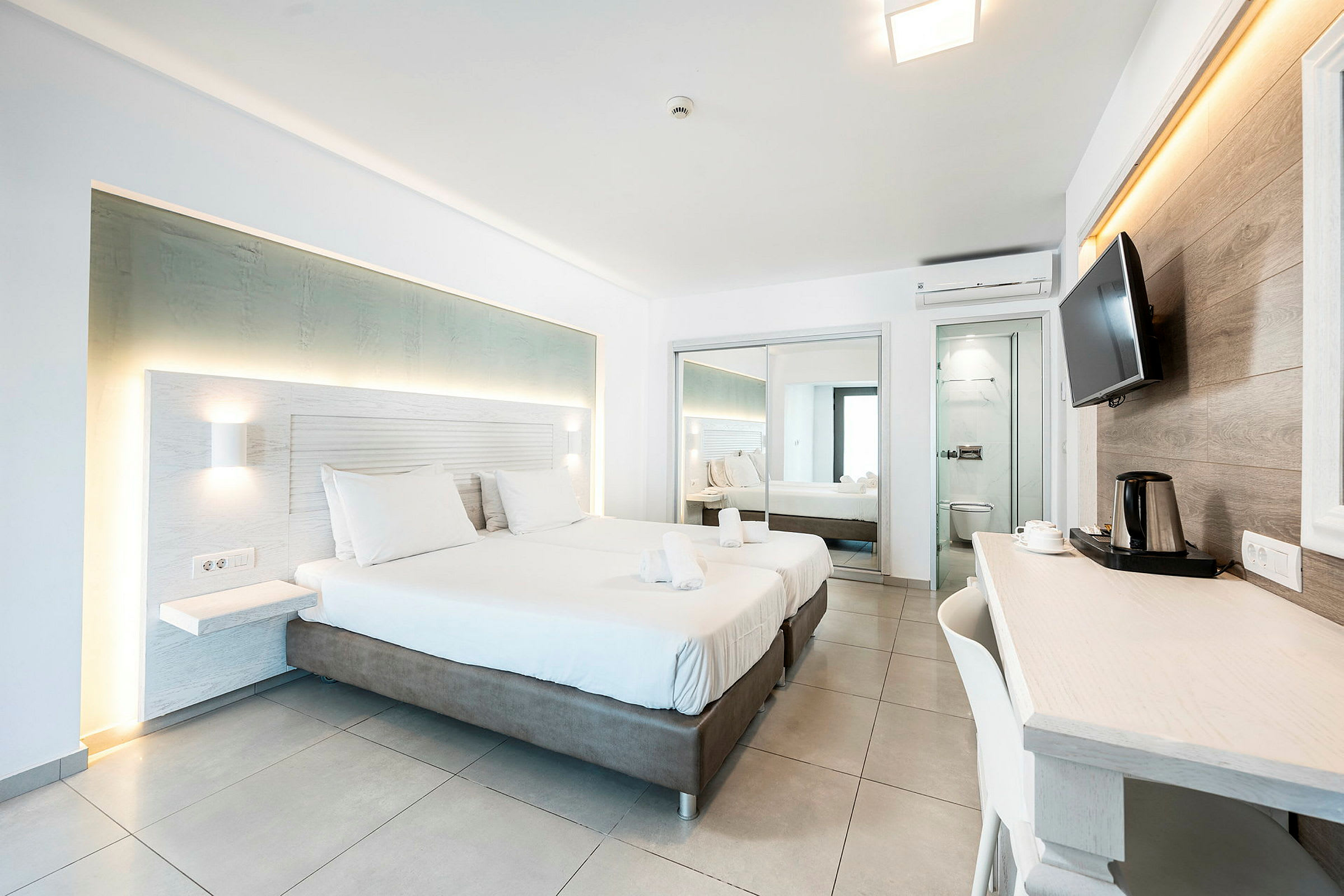 Moderne hotellrom med to senger, skrivebord og speil. (AI-generert tekst)