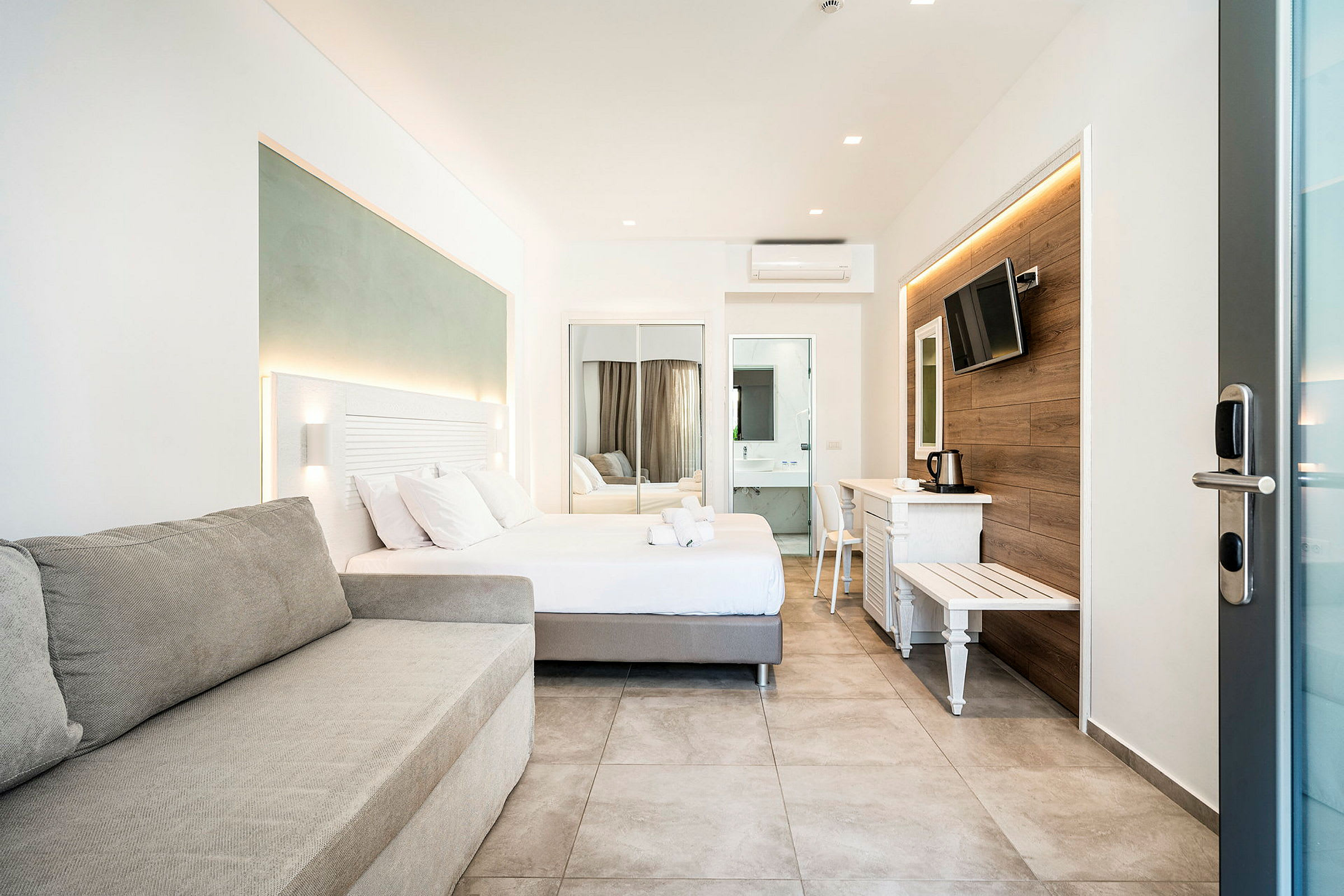 Moderne hotellrom med seng, sofa og TV. (AI-generert tekst)