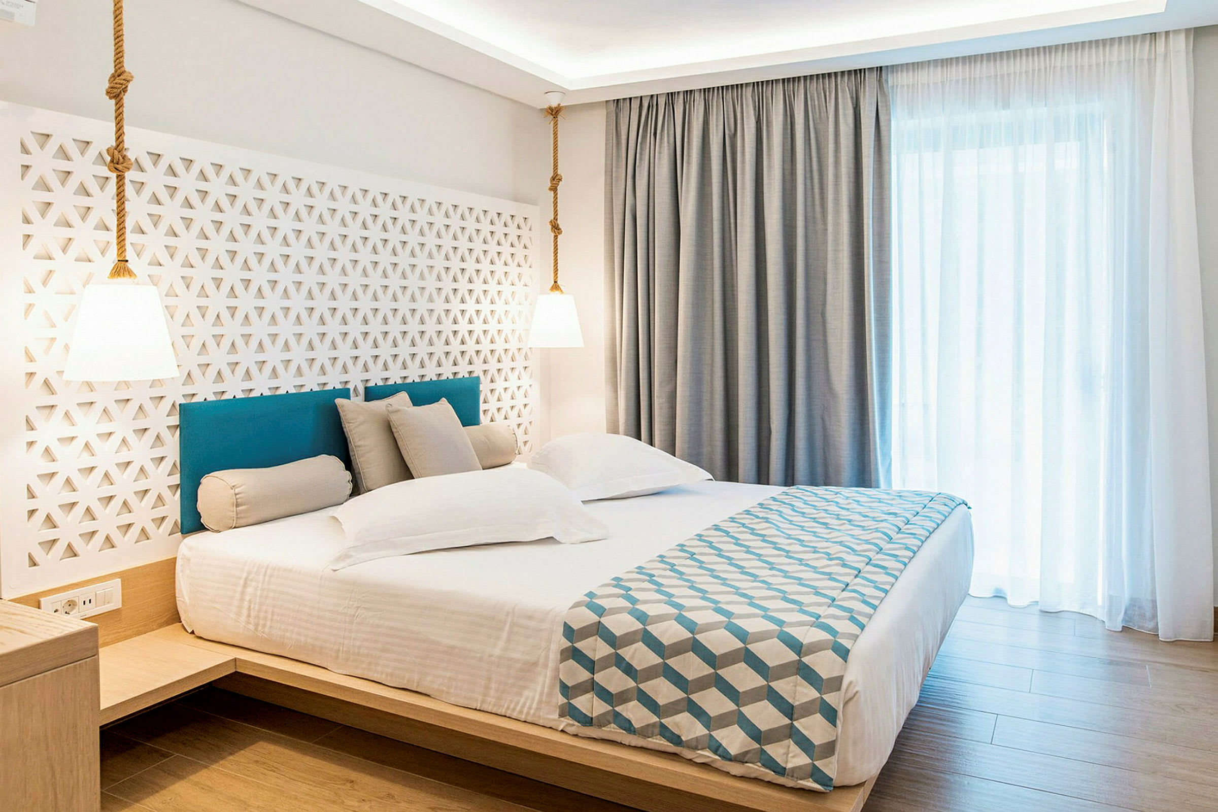 Hotellrom med en dobbeltseng, moderne innredning og lyse gardiner. (AI-generert tekst)
