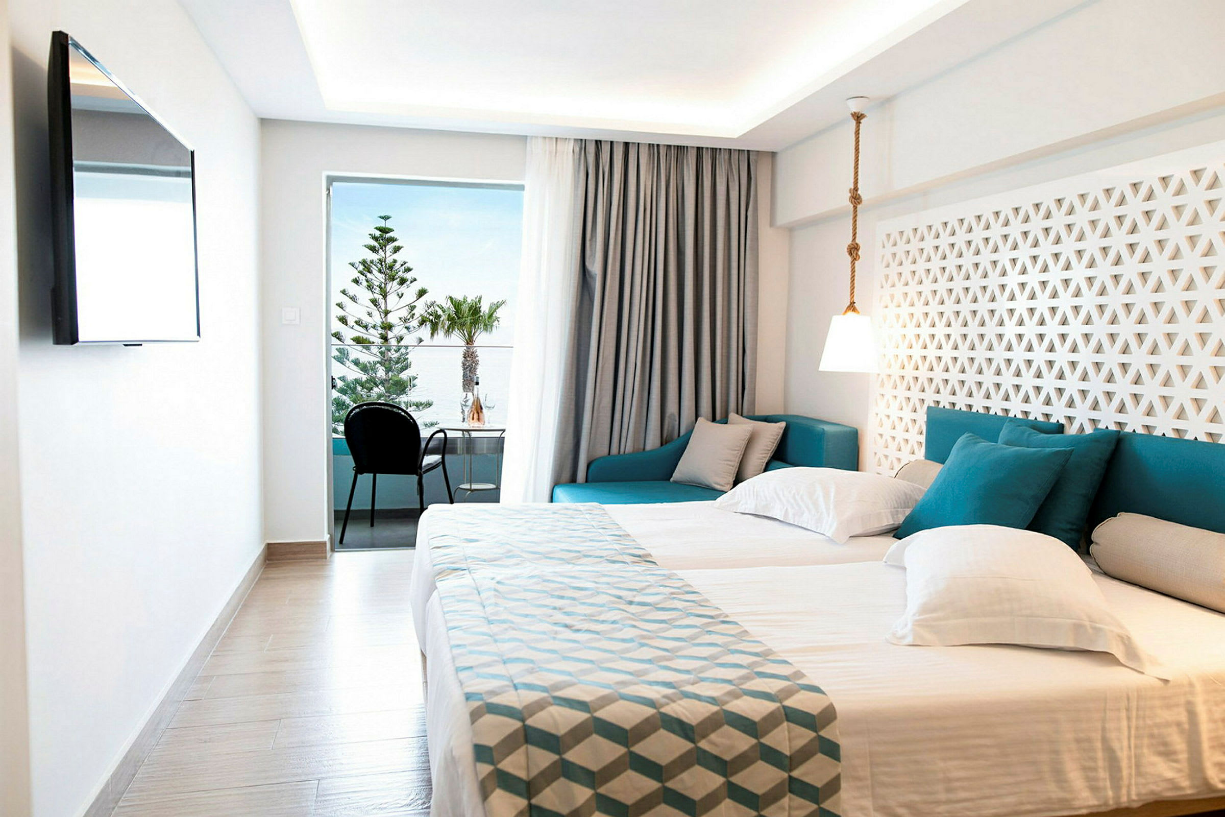Moderne hotellrom med dobbeltseng, sittegruppe og balkong med utsikt. (AI-generert tekst)