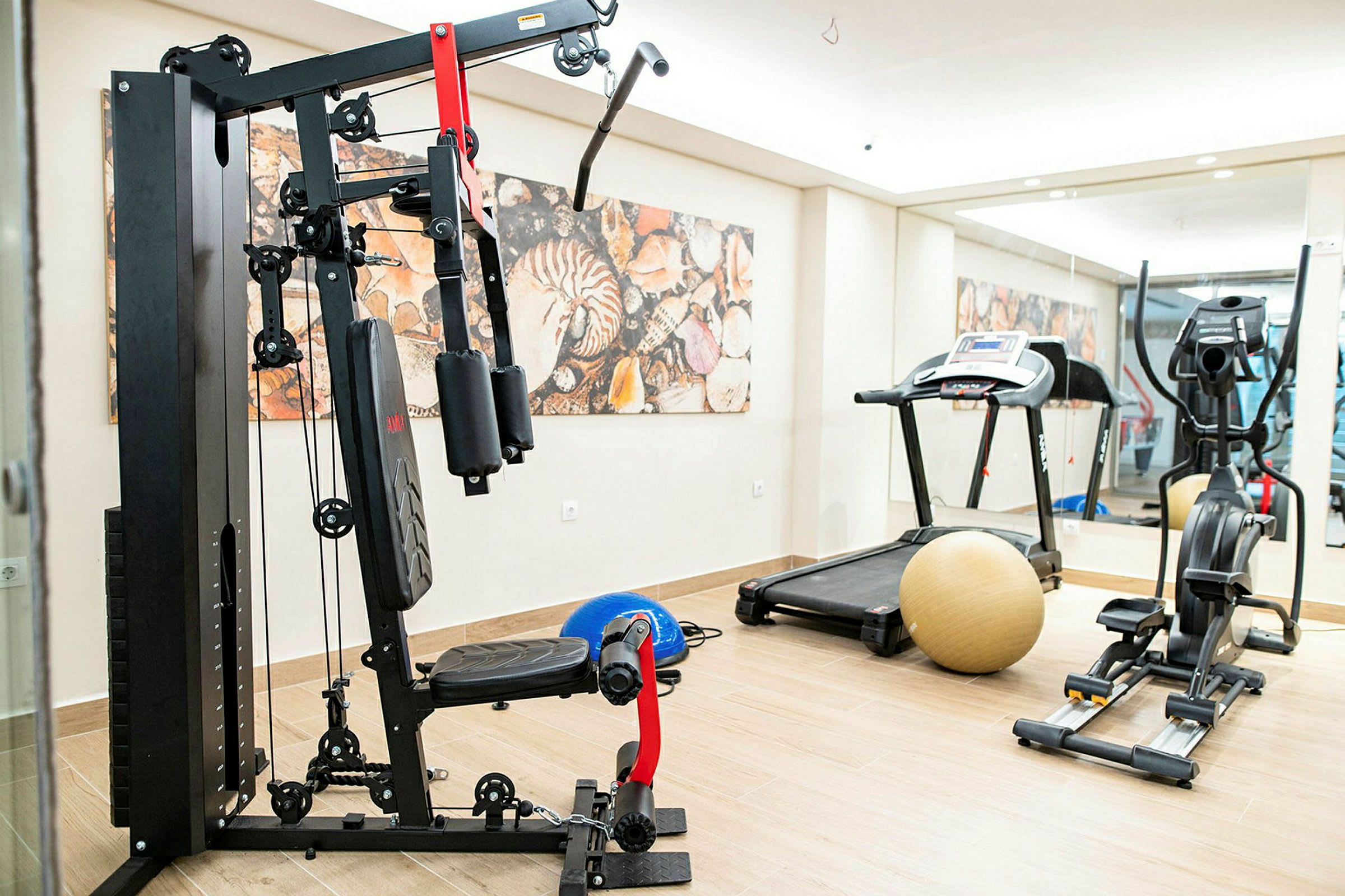 Bilde av et treningsstudio med treningsutstyr, inkludert en vektmaskin, en tredemølle og en ergometersykkel. (AI-generert tekst)