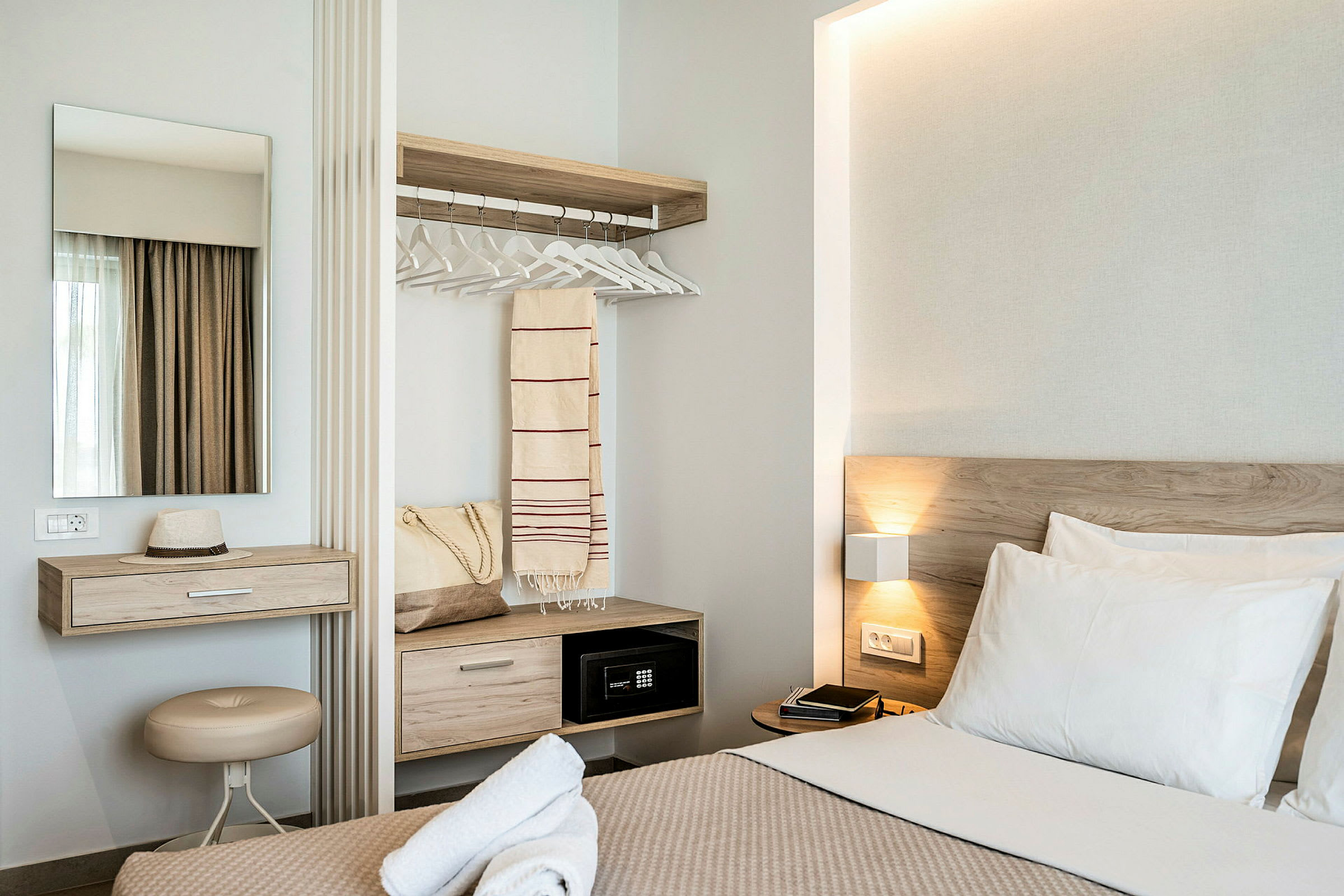 Moderne hotellrom med seng, skrivebord, speil og garderobe. (AI-generert tekst)