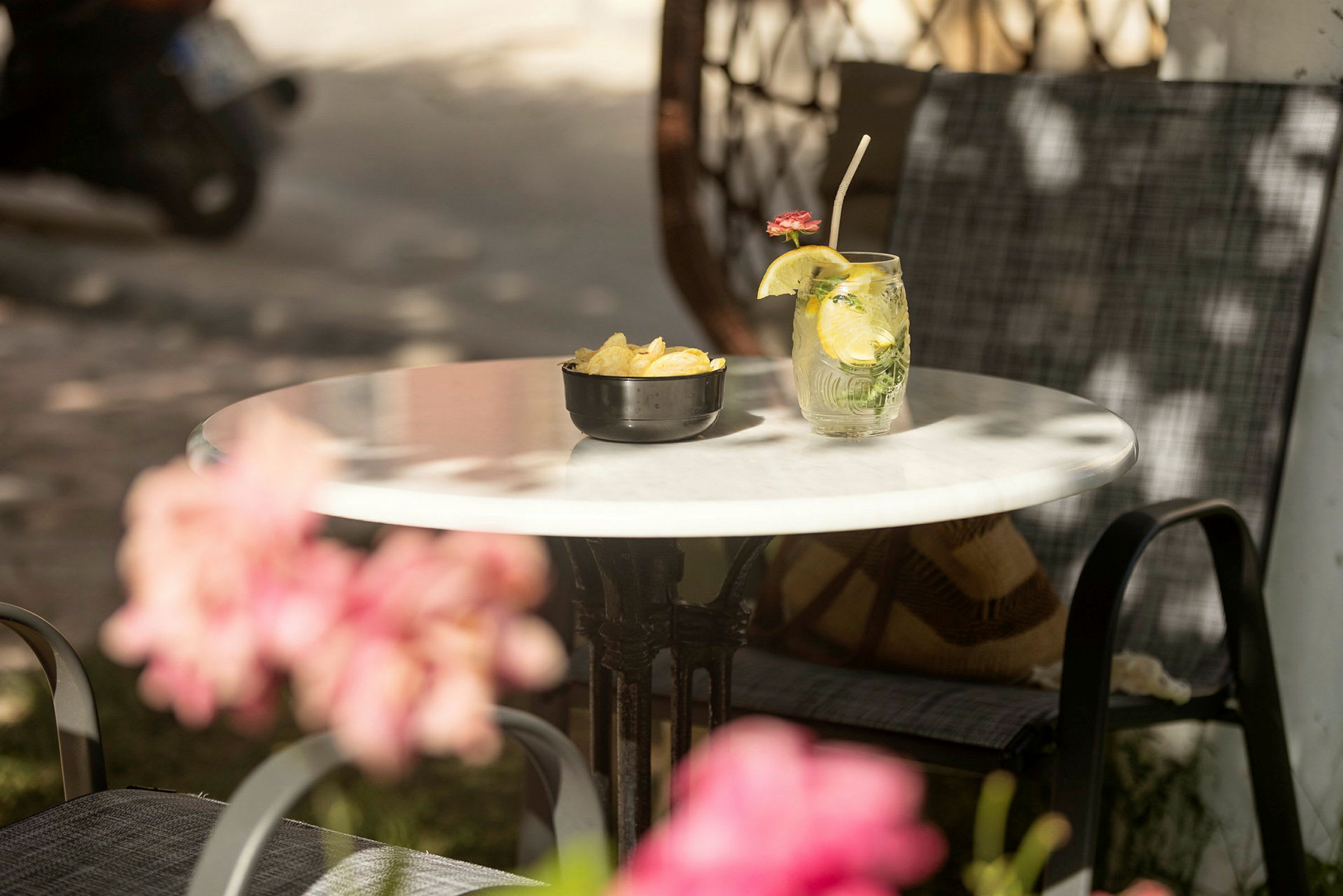 Et bord med en skål chips og et glass med en drink dekorert med en sitronskive og en blomst. (AI-generert tekst)