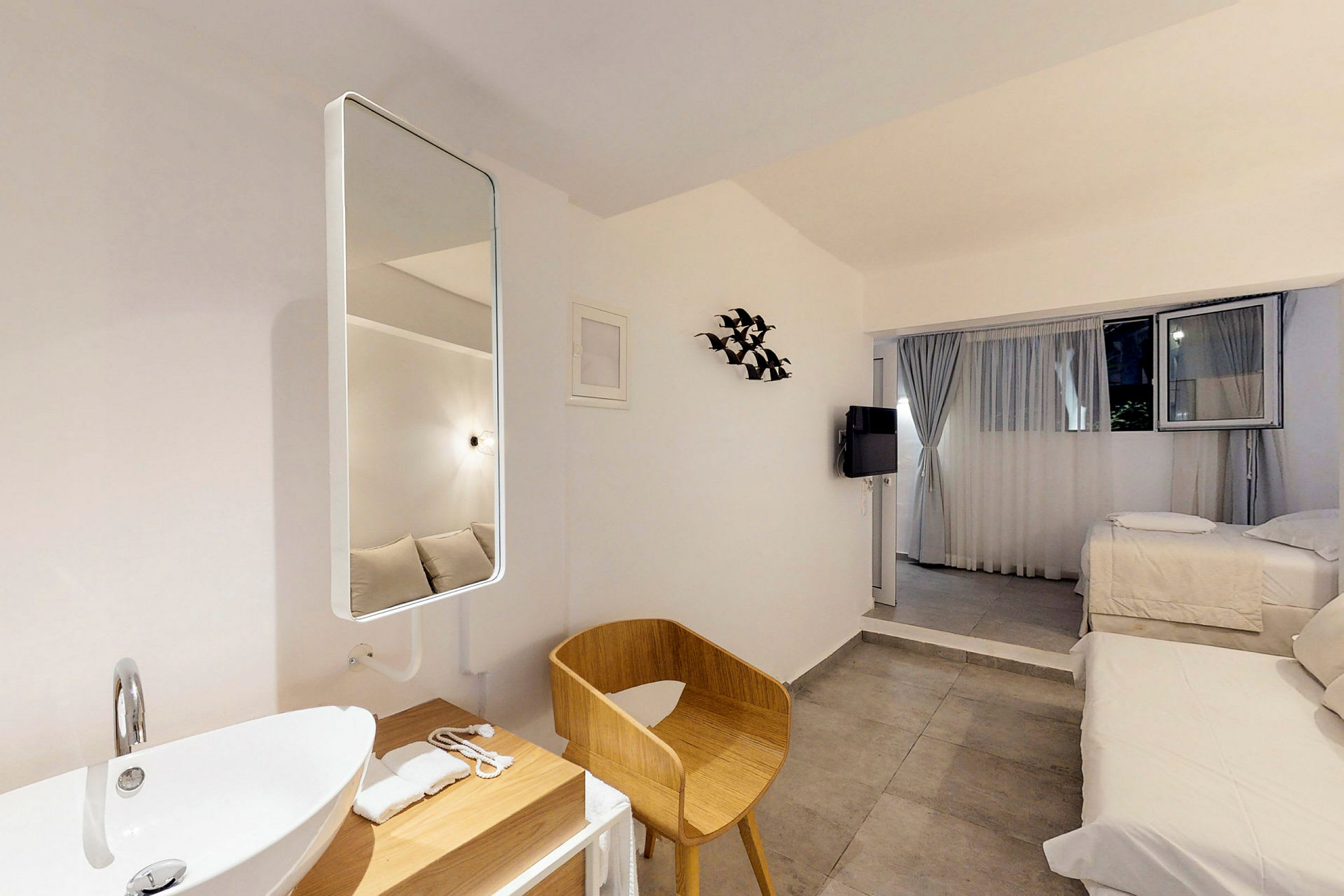 Moderne og lyst hotellrom med senger, en sitteplass og en servant. (AI-generert tekst)