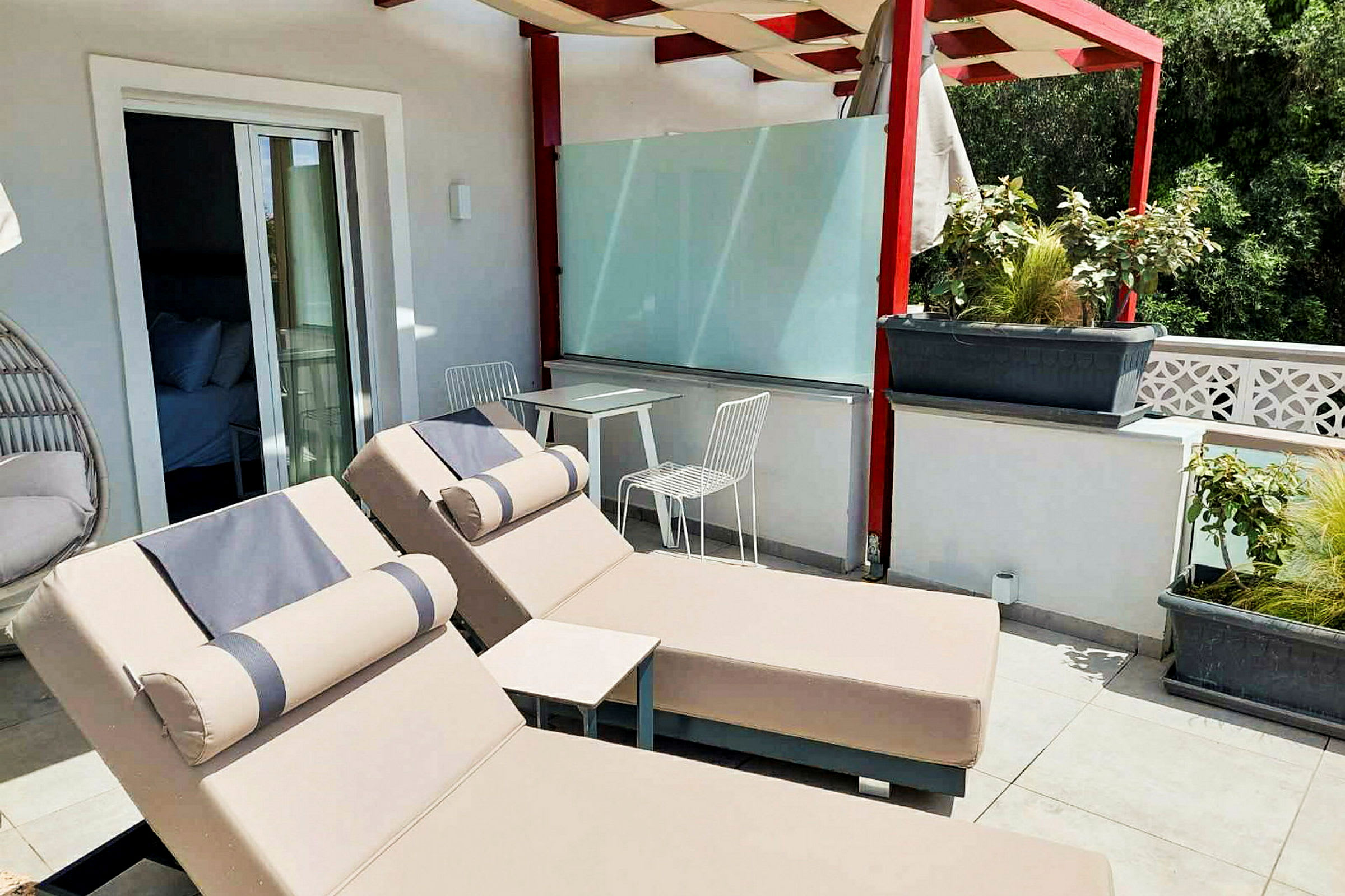 Terrasse med to solsenger og et bord med to stoler under en pergola. (AI-generert tekst)