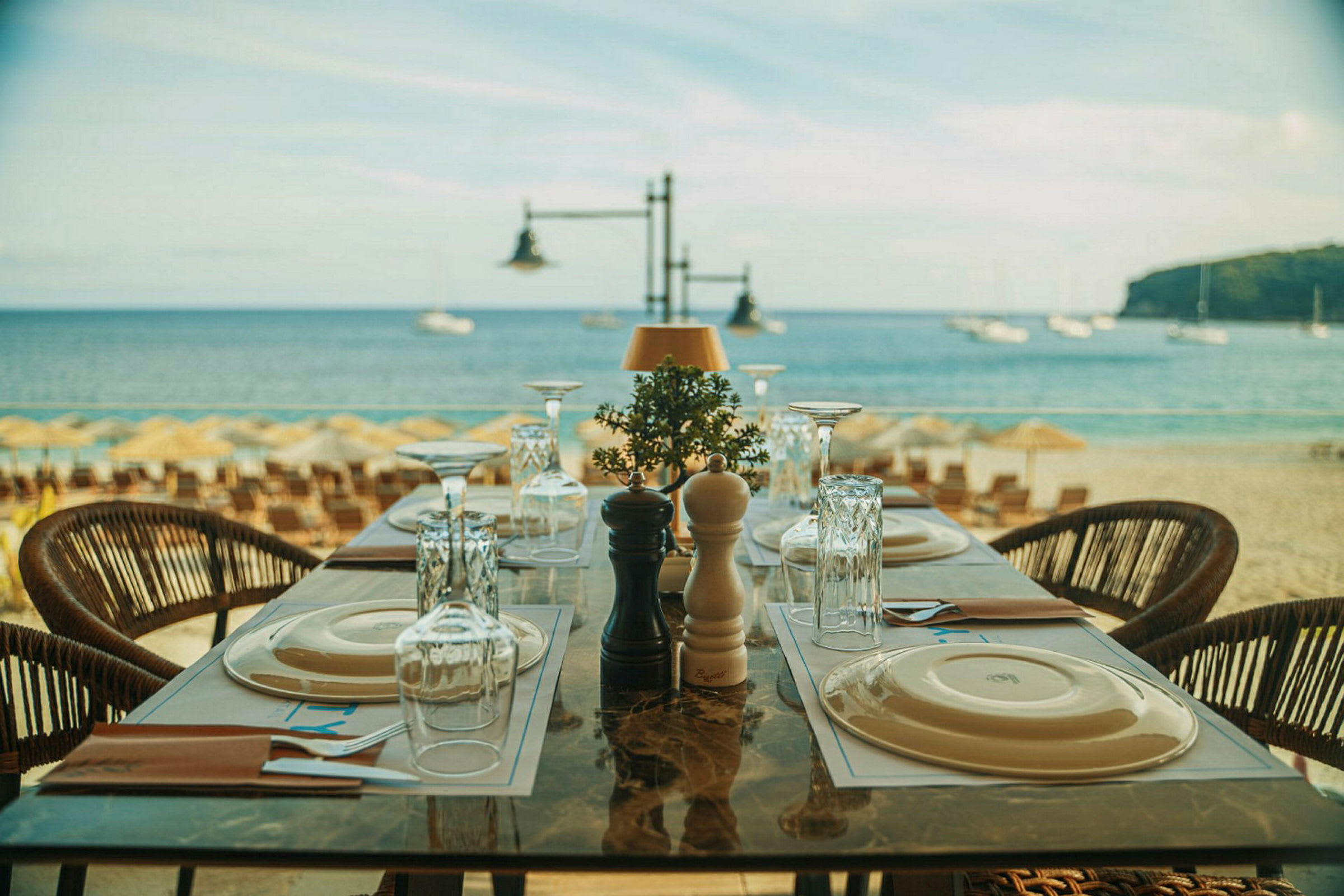 Et dekket bord på en restaurant ved stranden med havet i bakgrunnen. (AI-generert tekst)
