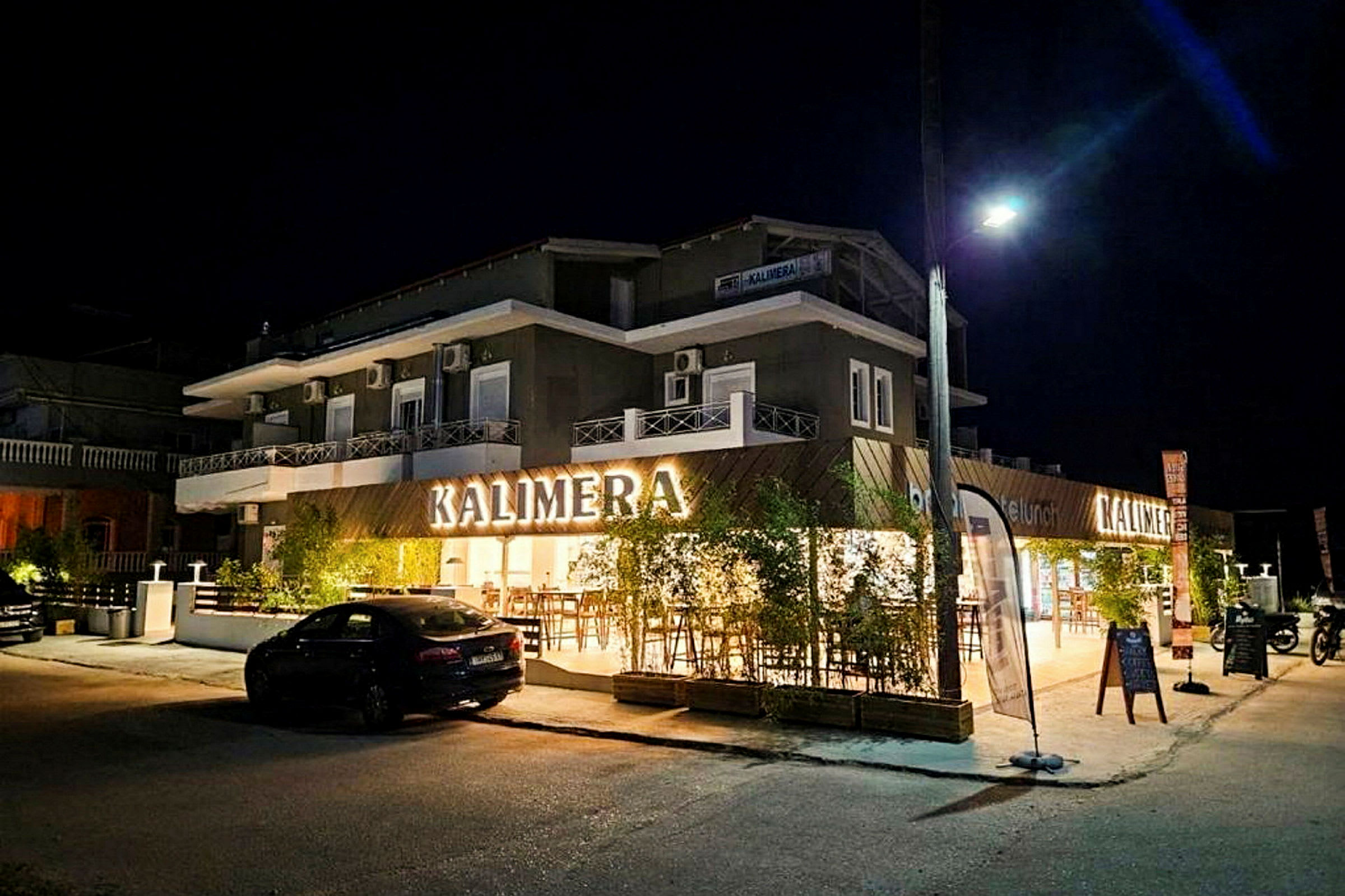 En bygningfasade med skiltet 'KALIMERA', tatt om kvelden. (AI-generert tekst)