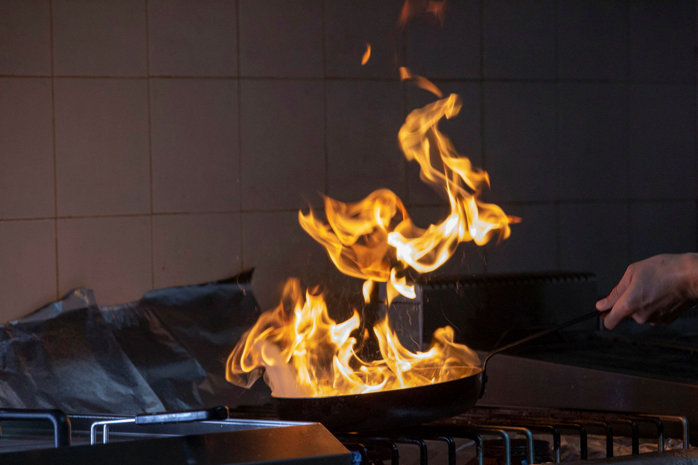 Flammer fra en stekepanne på en komfyr. (AI-generert tekst)
