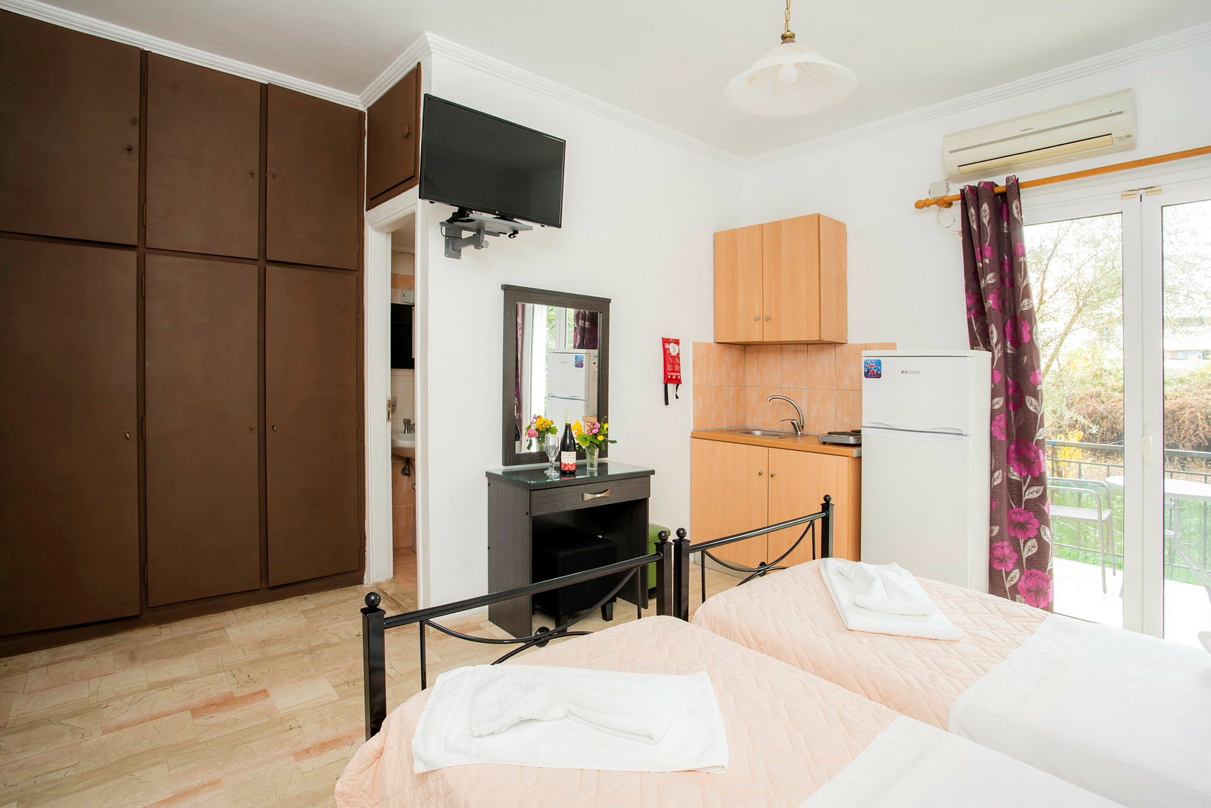 Hotellrom med to enkeltsenger, kjøkken, garderobeskap og vindu. (AI-generert tekst)