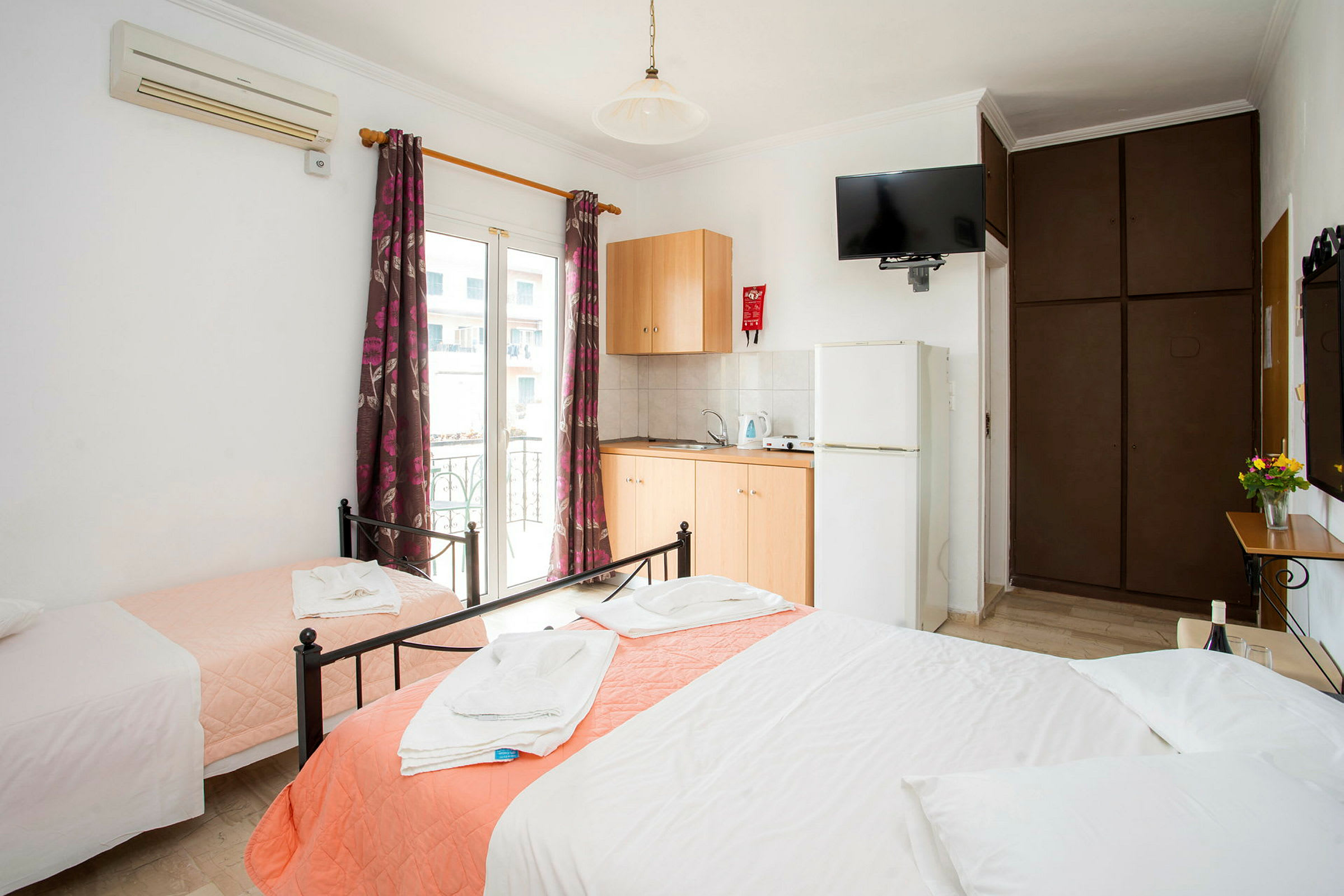 Hotellrom med tre senger, garderobe, klimaanlegg og tekjøkken. (AI-generert tekst)