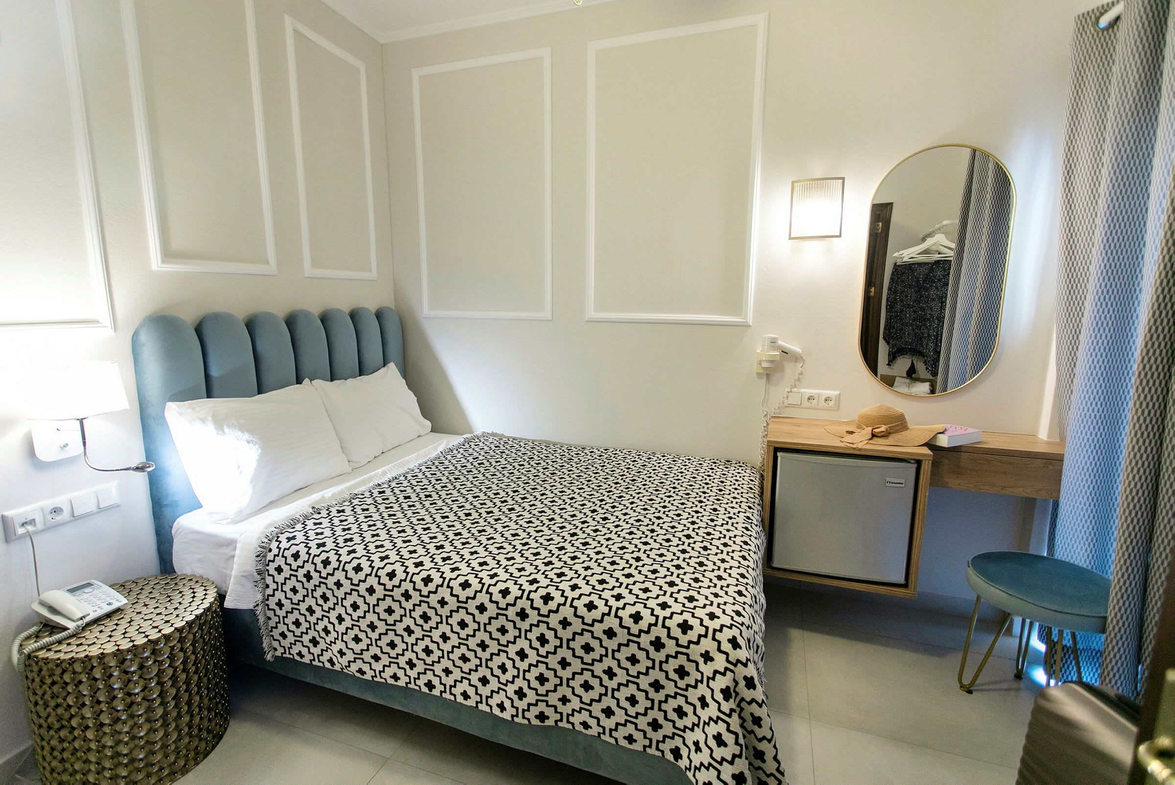 Et hotellrom med en seng, et nattbord og et speil. (AI-generert tekst)