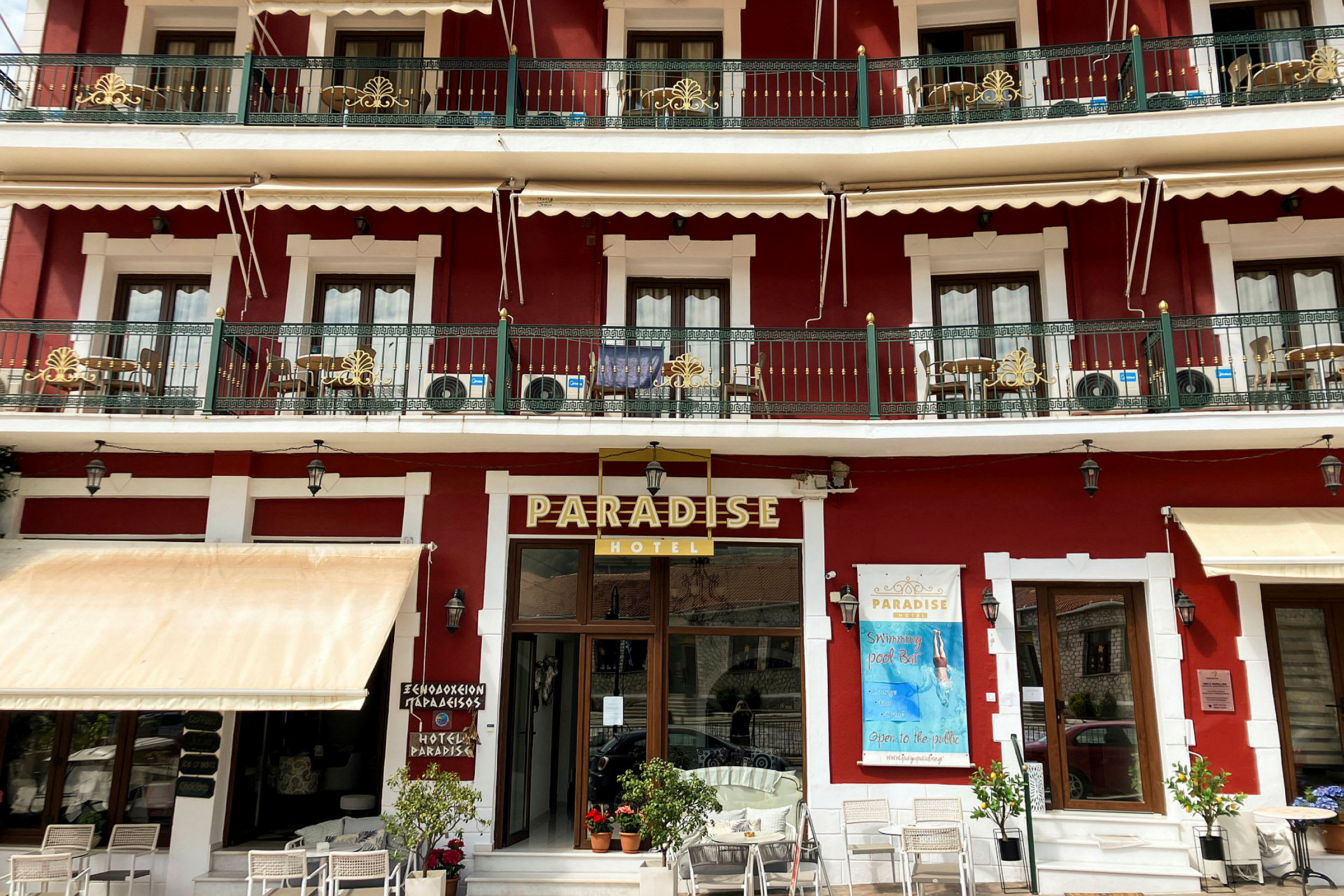 To etasjer av Paradise-hotellet i en rød bygning med balkonger og hvit dekorasjon. (AI-generert tekst)