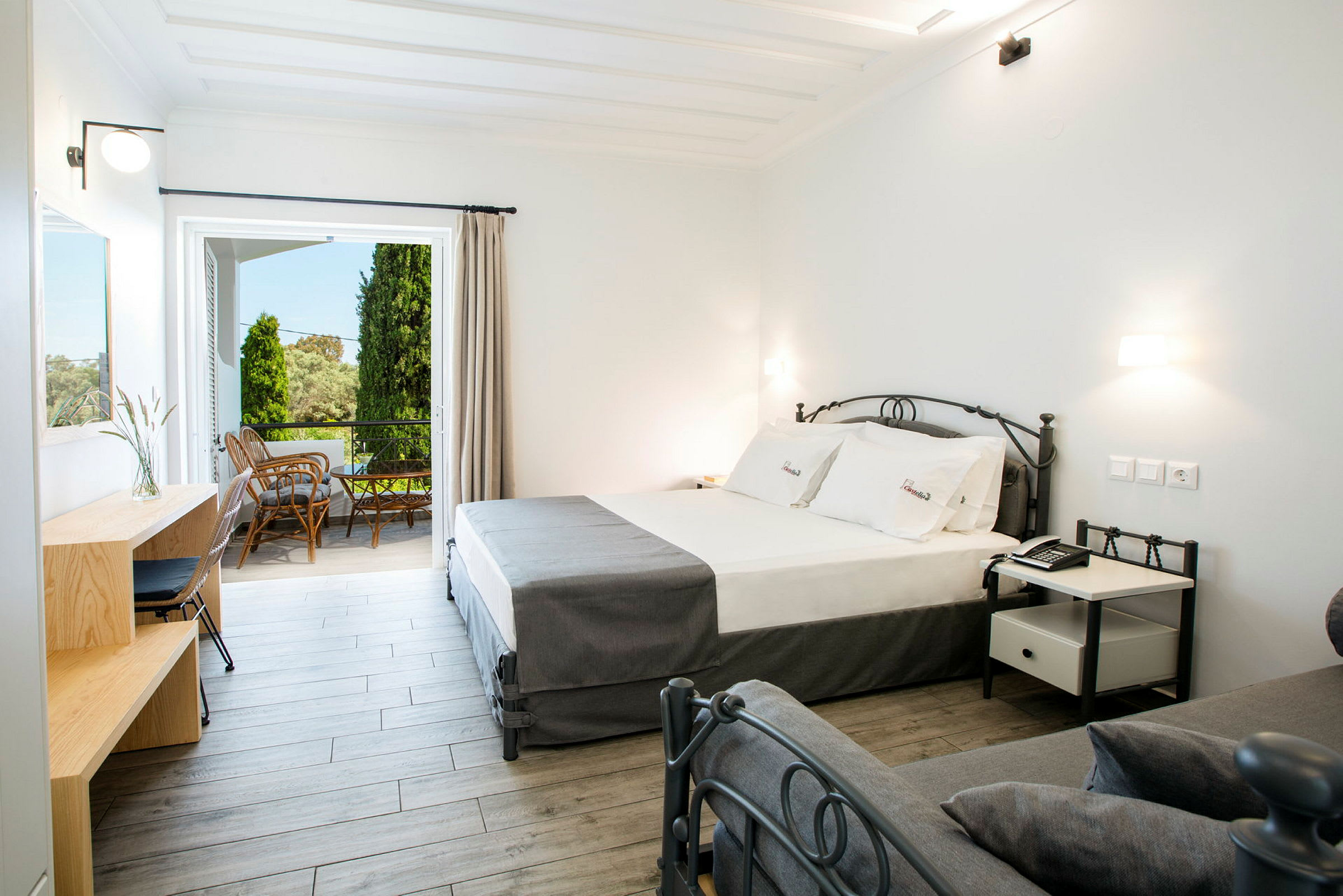 Moderne hotellrom med seng, skrivebord og utgang til møblert balkong. (AI-generert tekst)