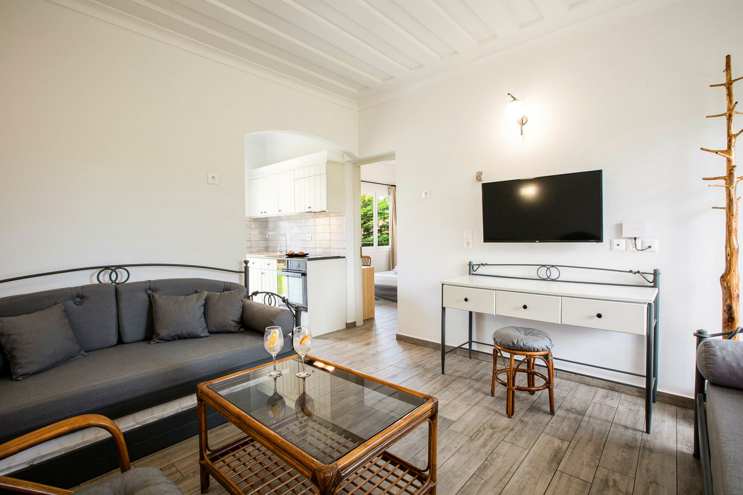 Stue med sofa, glassbord og en TV på veggen. (AI-generert tekst)