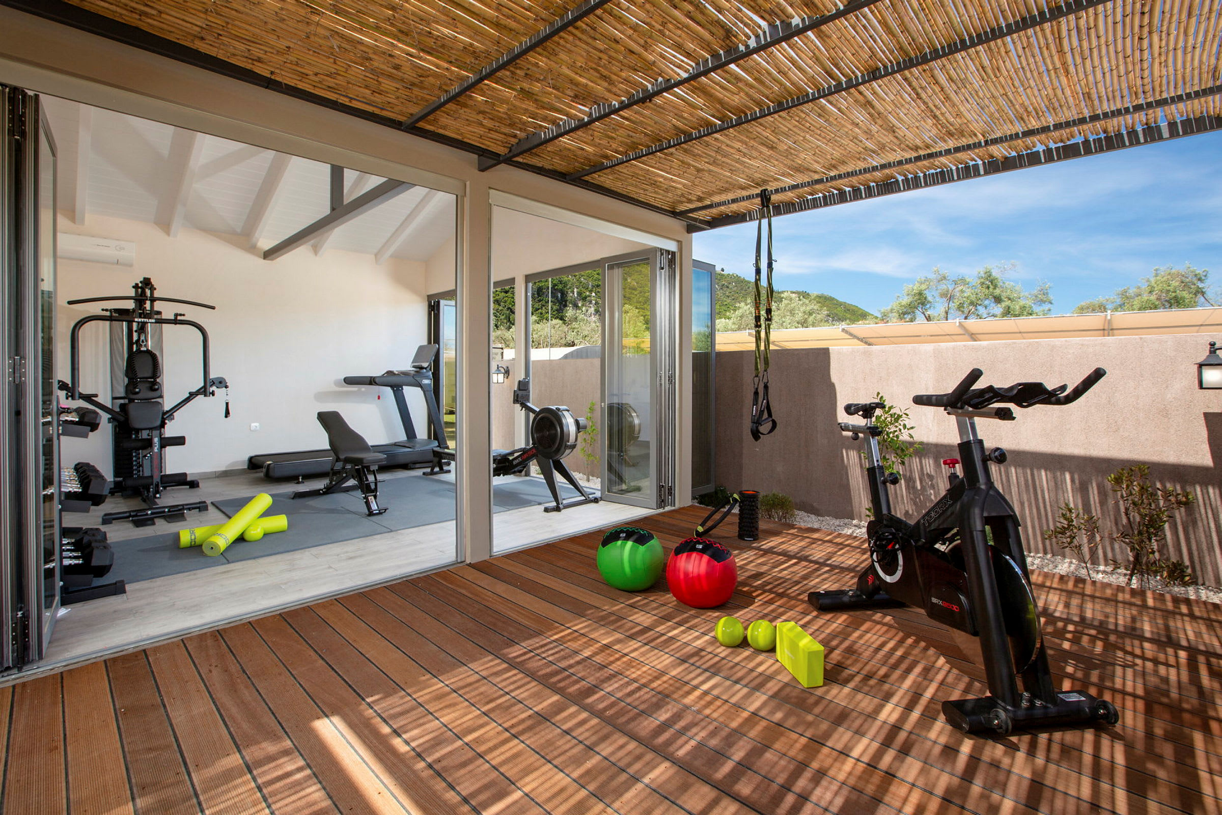 Bilde av et treningsstudio med treningsutstyr som ellipsemaskin, yogamatter, hantler og pilatesballer. (AI-generert tekst)