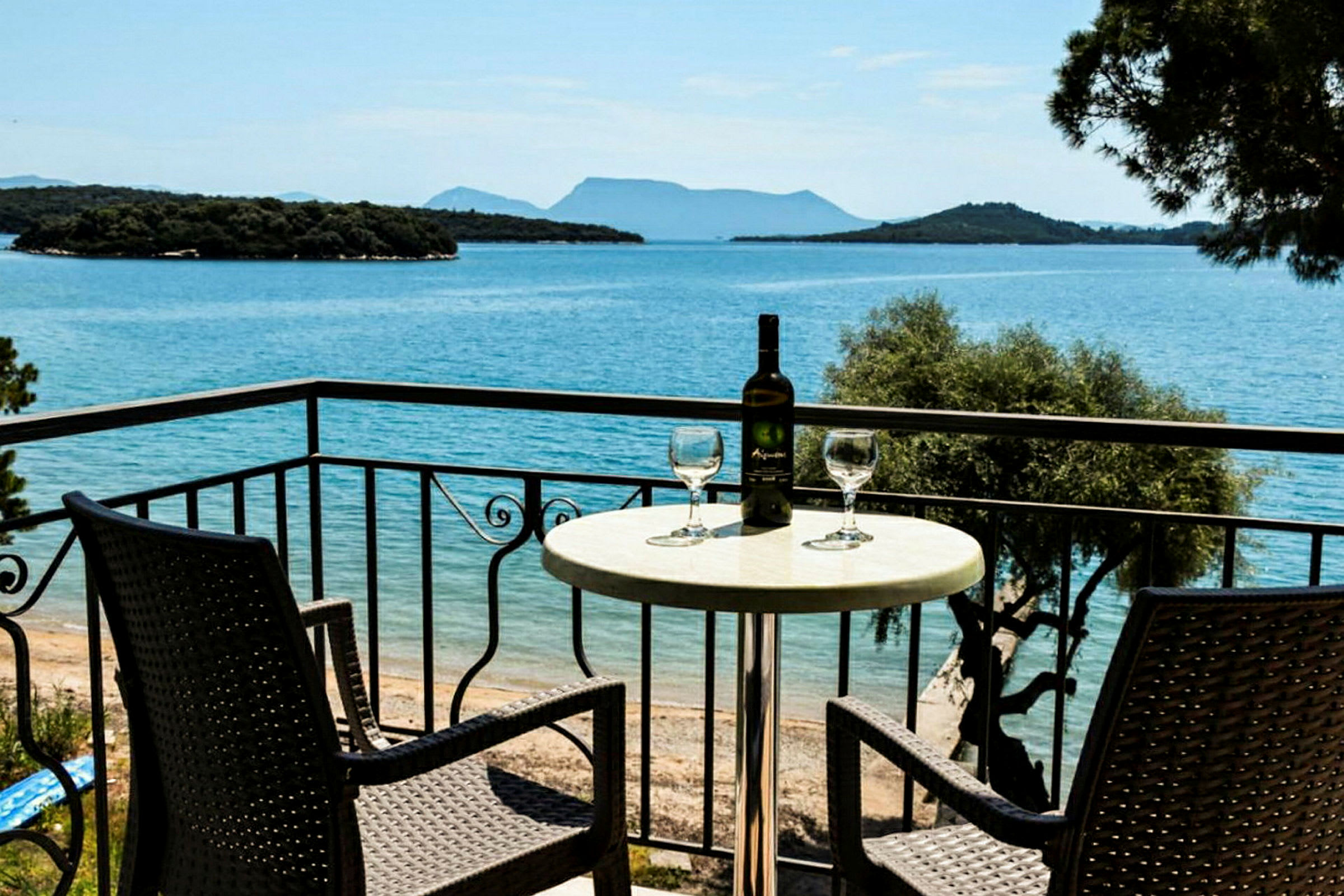 To stoler og et bord med en vinflaske og glass på en balkong med utsikt over havet. (AI-generert tekst)