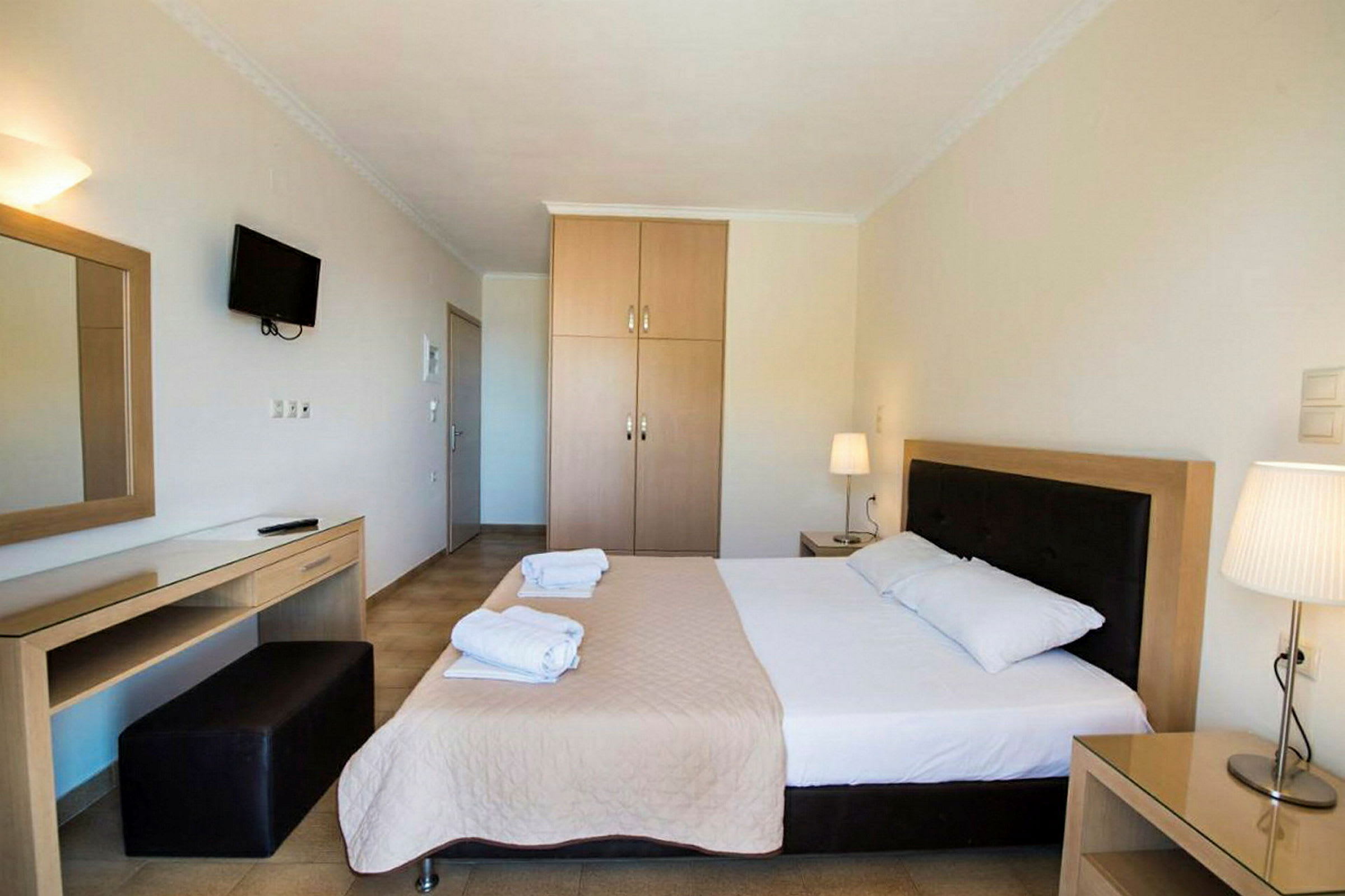 Hotellrom med en dobbeltseng, nattbord, garderobe og skrivebord. (AI-generert tekst)