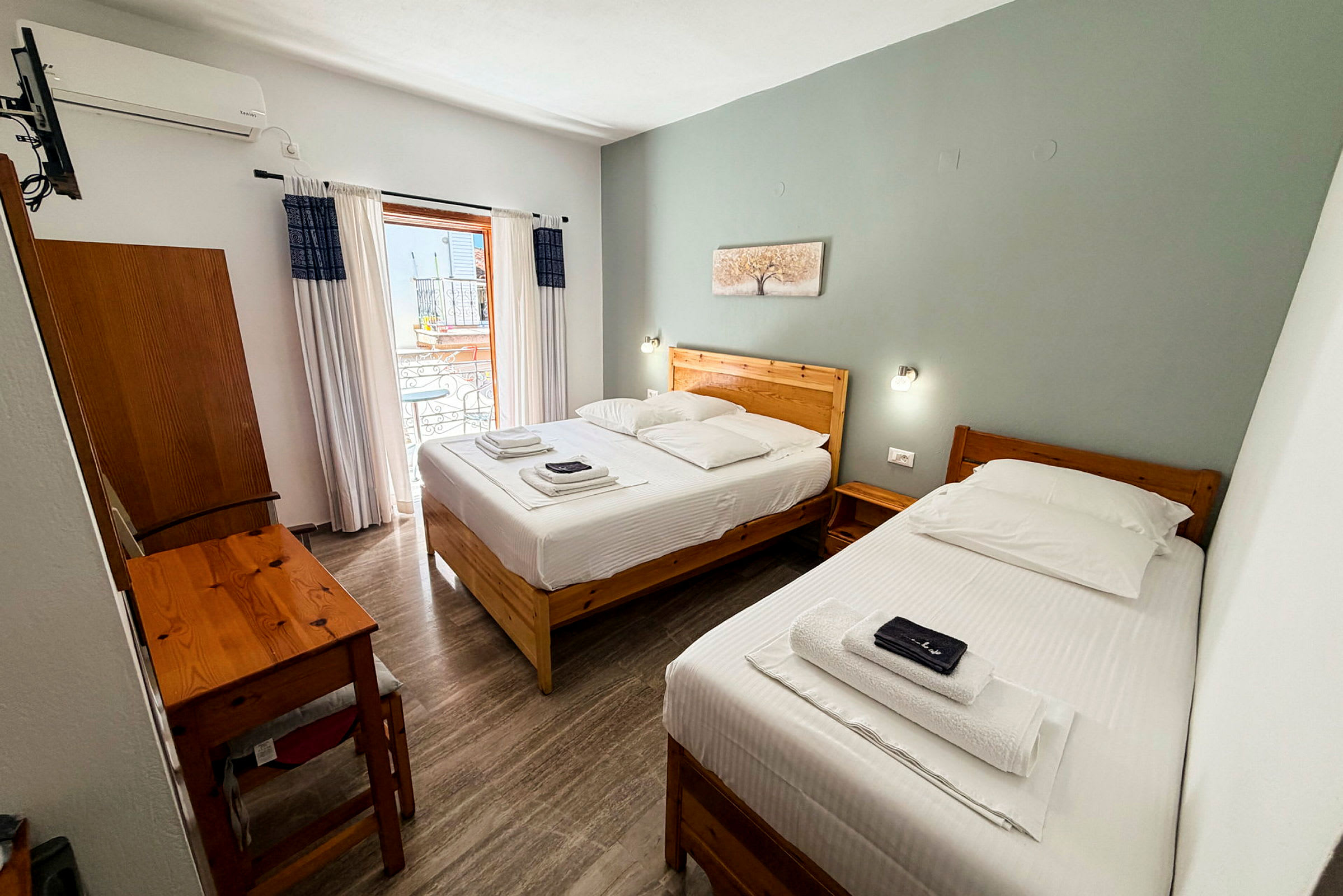 Hotellrom med to enkeltsenger, et skrivebord og en balkong. (AI-generert tekst)