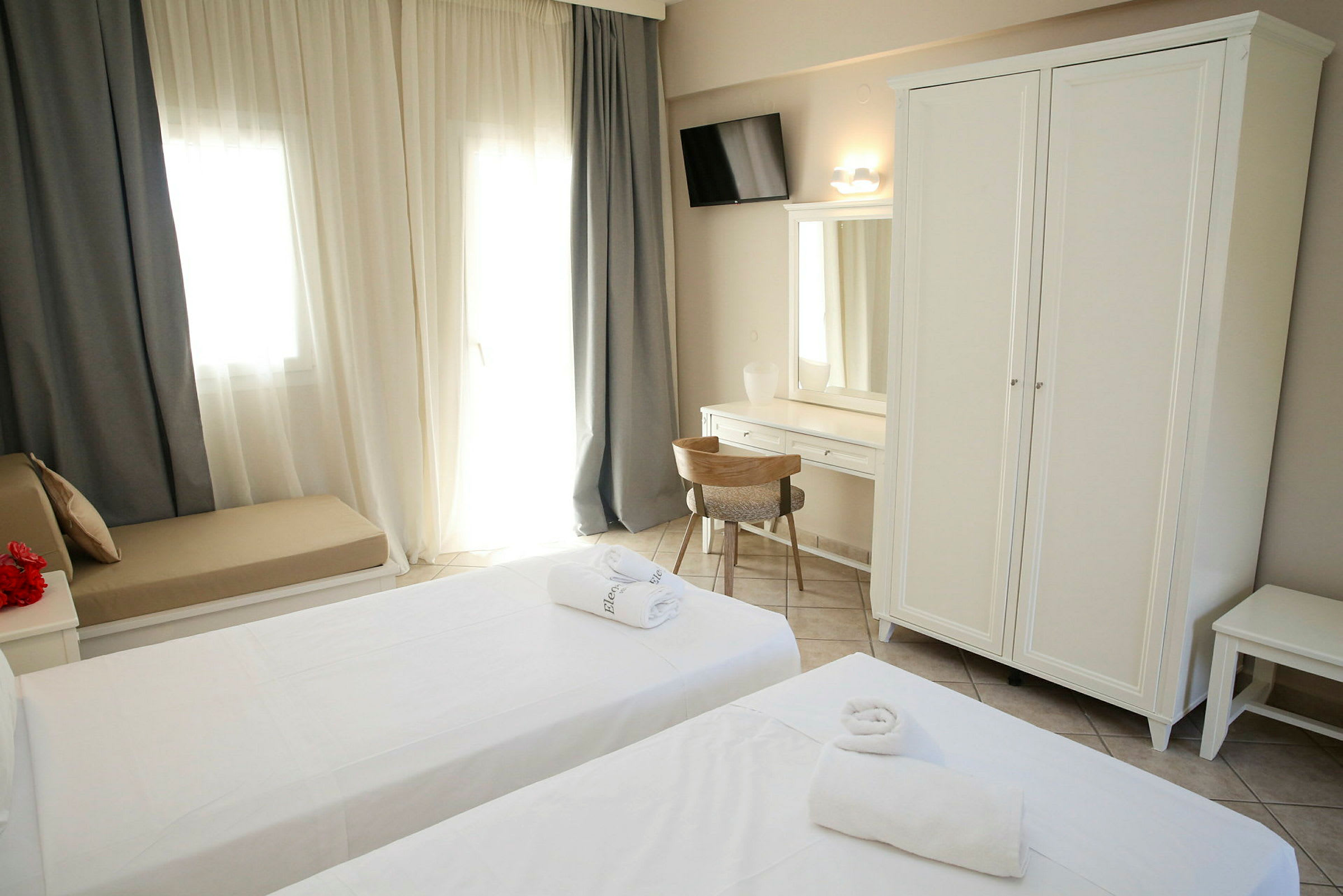 Bilde av et hotellrom med to senger, hvit garderobe og skrivebord. (AI-generert tekst)