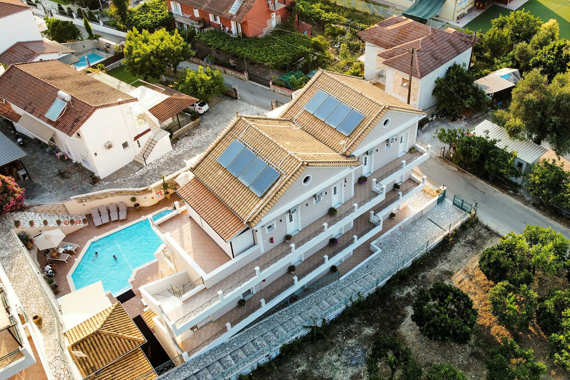 Luftfoto av villa med basseng og omkringliggende hus. (AI-generert tekst)