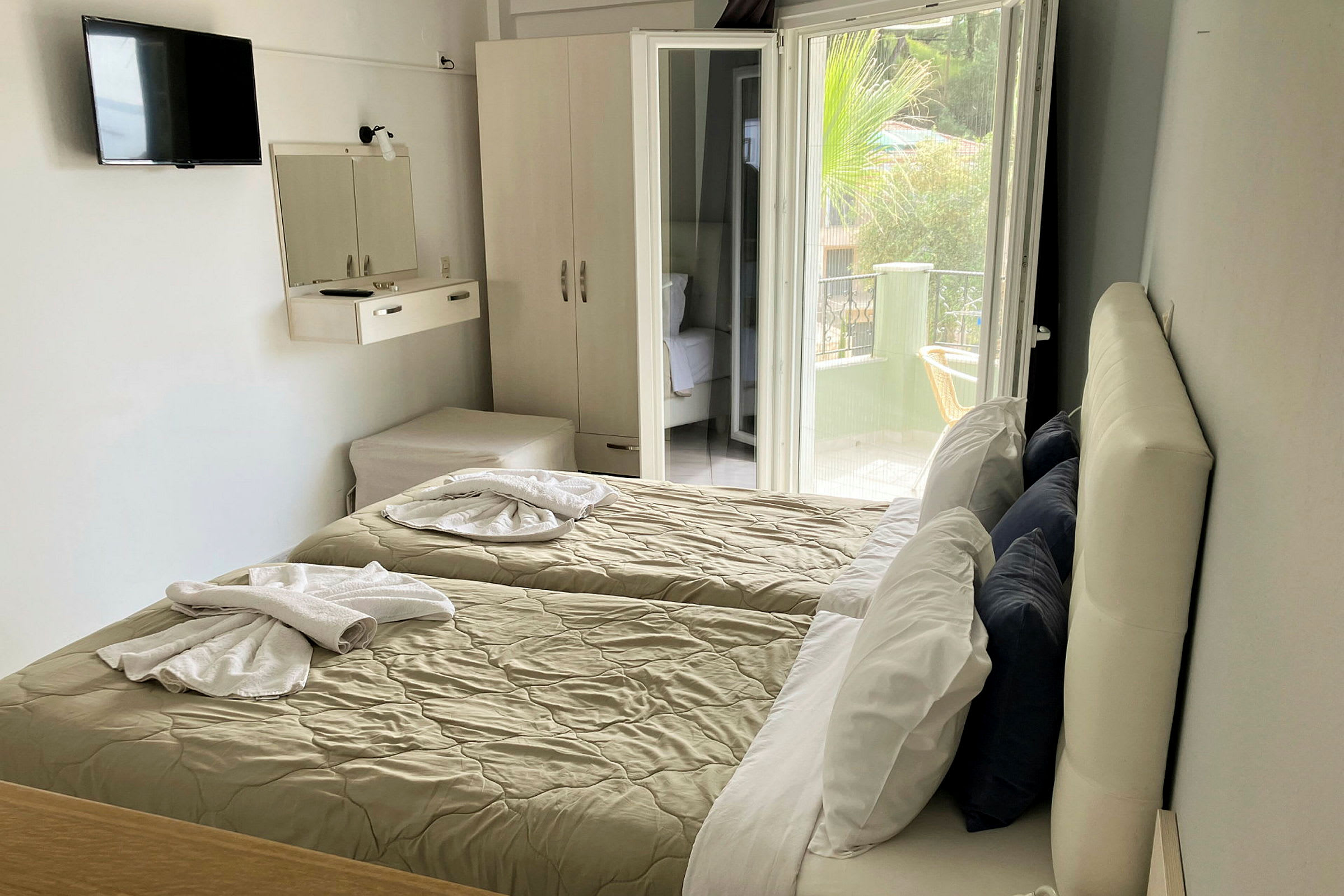 Hotellrom med to enkeltsenger, garderobe og åpen balkongdør. (AI-generert tekst)