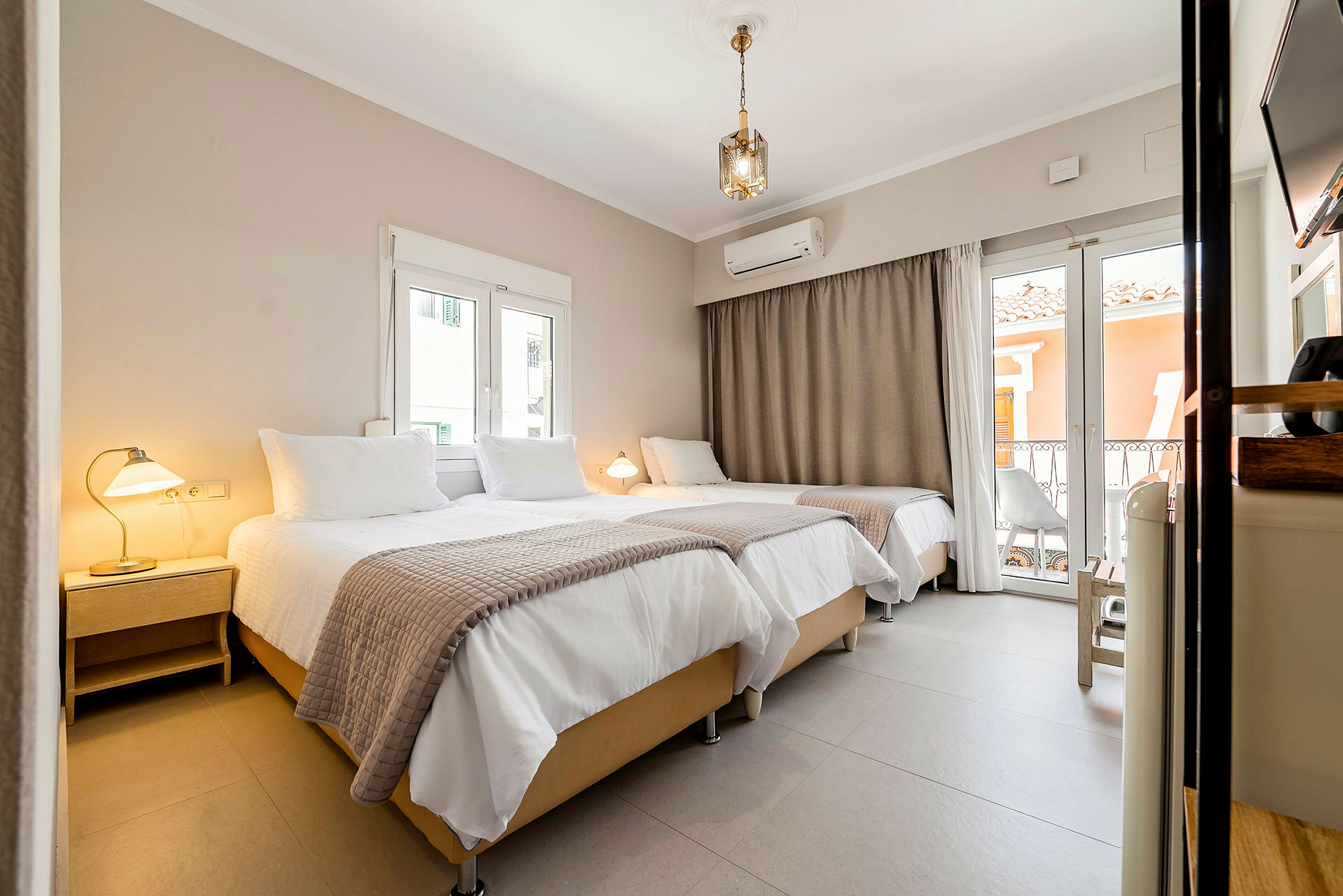 Interiør av et hotellrom med tre senger, lamper og vinduer. (AI-generert tekst)
