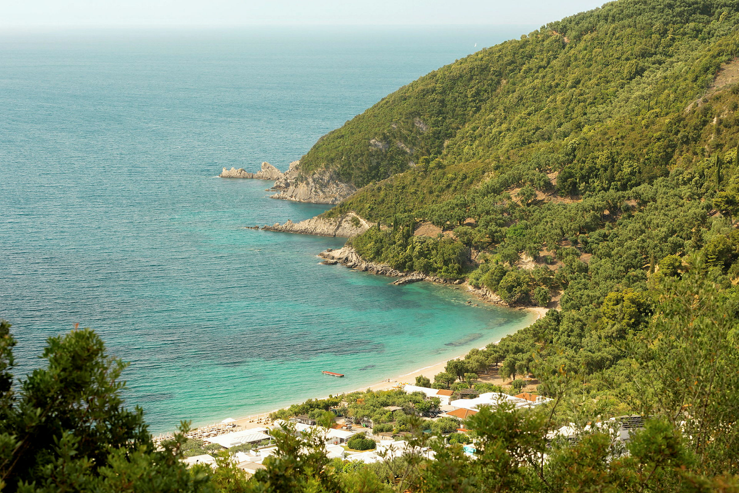 En kystlinje med frodige klipper og en strand ved turkis vann. (AI-generert tekst)