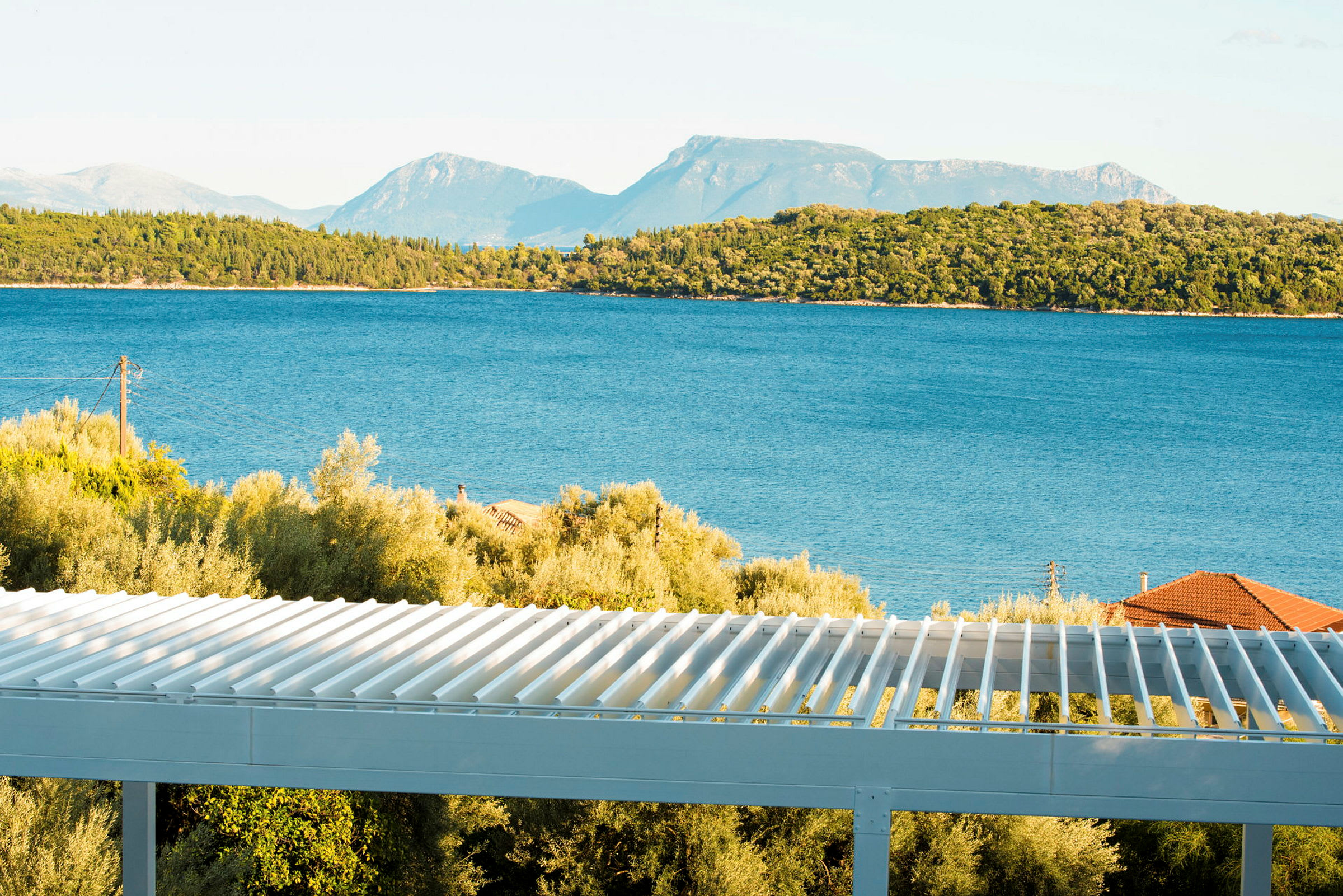 Utsikt over havet med trær og en terrasse i forgrunnen. (AI-generert tekst)