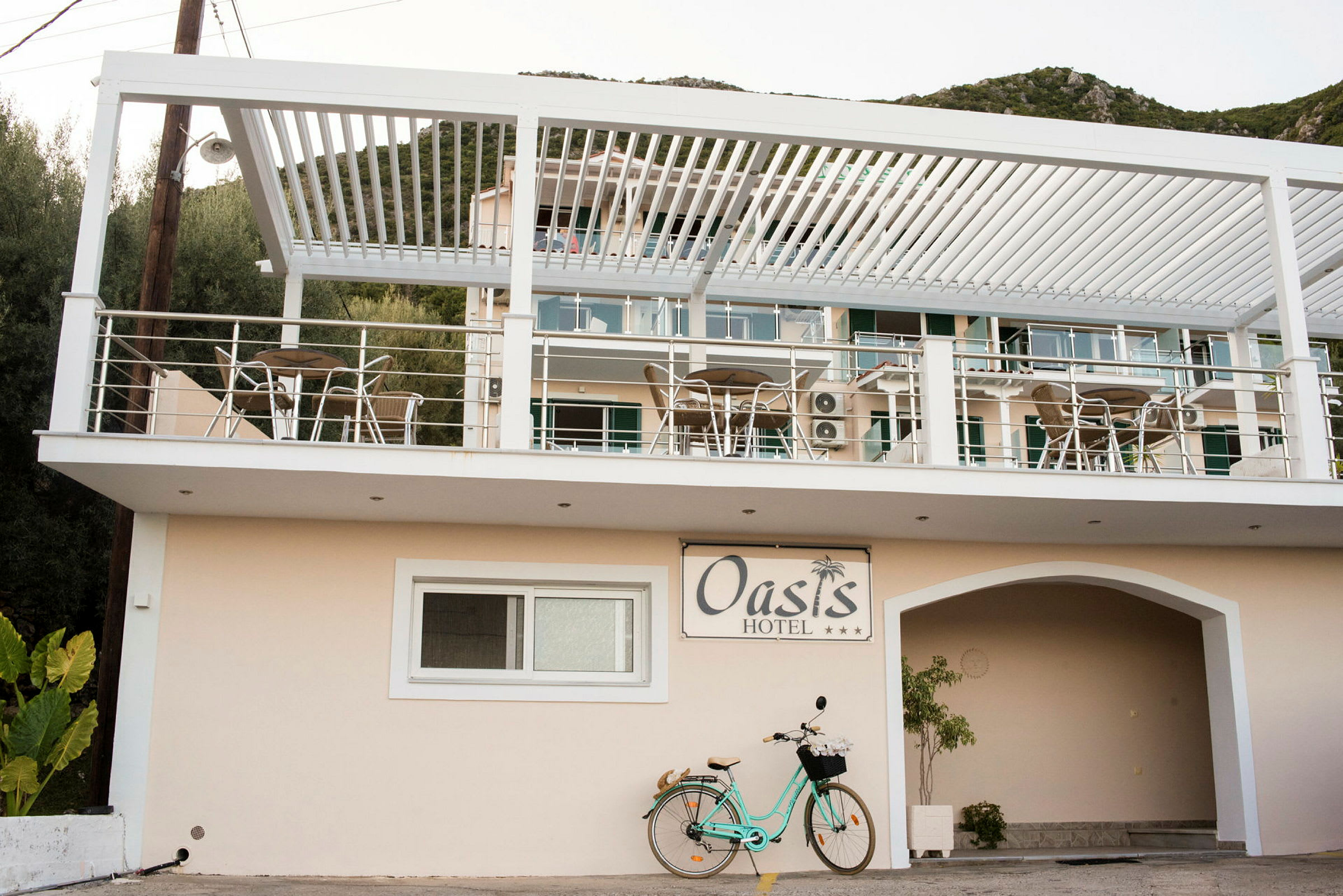Bilde av Oasis Hotel med balkonger og utemøbler samt en sykkel parkert nedenfor. (AI-generert tekst)