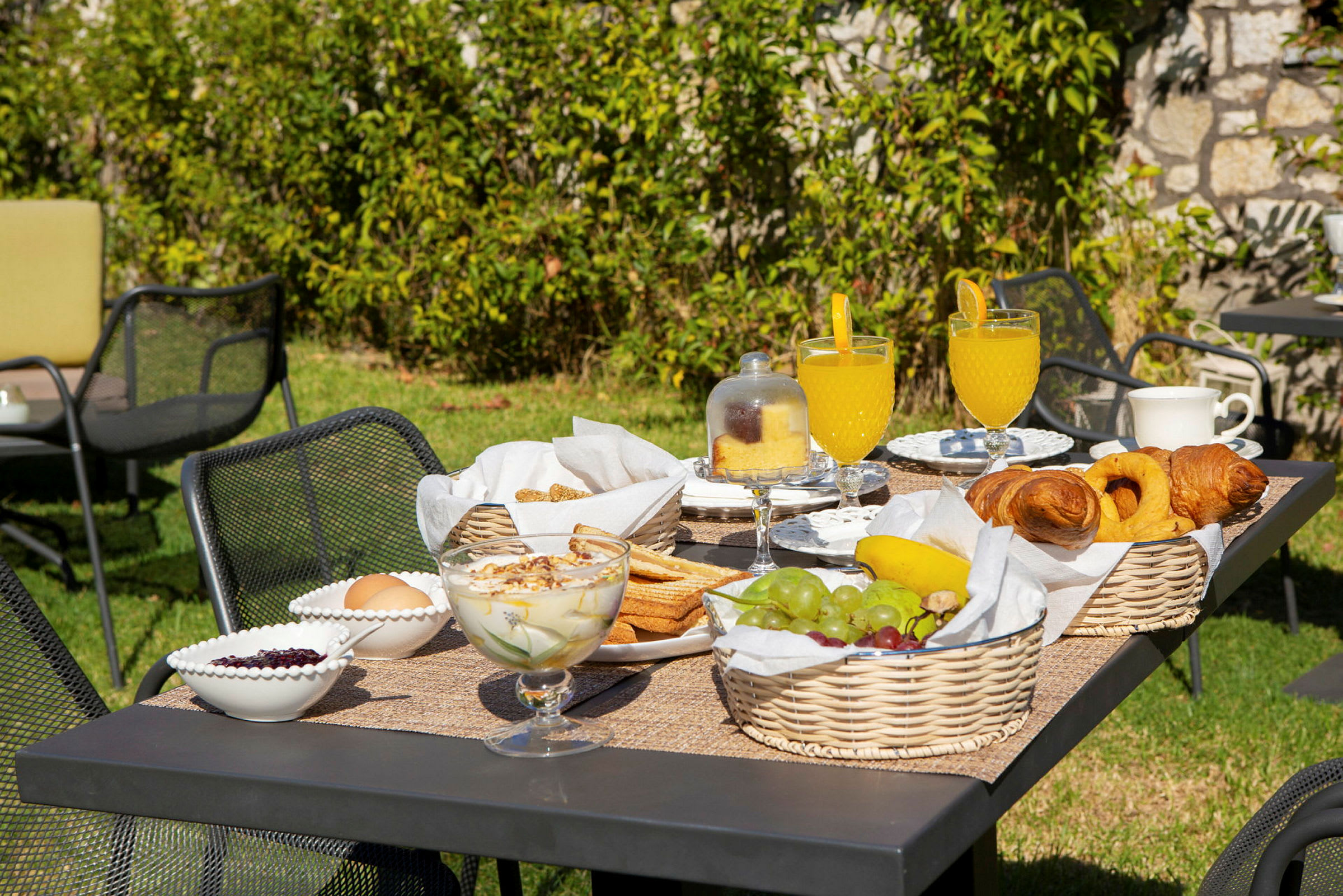 Hagebord med frokost som inneholder frukt, bakverk og drikke. (AI-generert tekst)