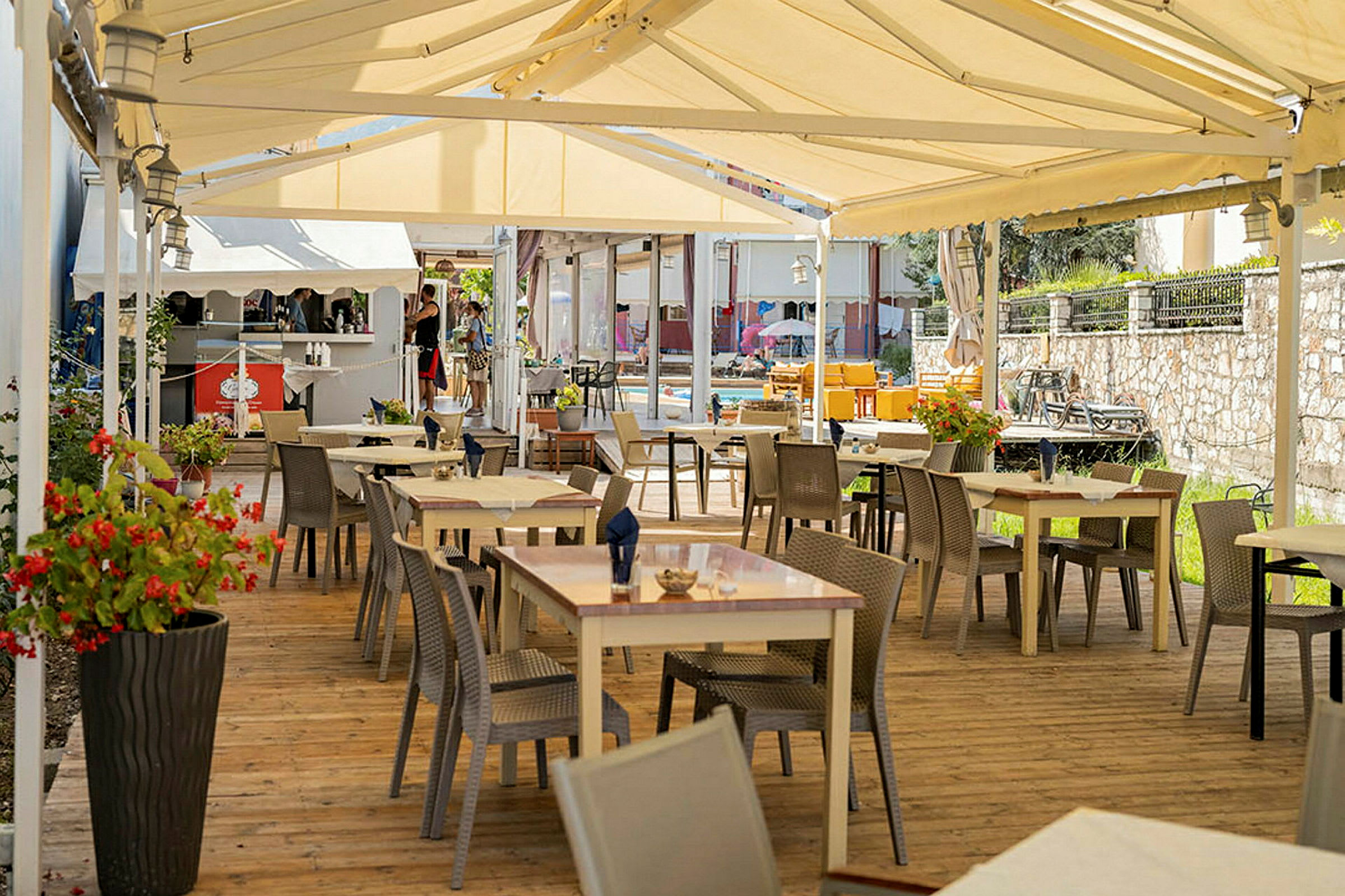 Utendørs restaurant med bord og stoler under et telt. (AI-generert tekst)