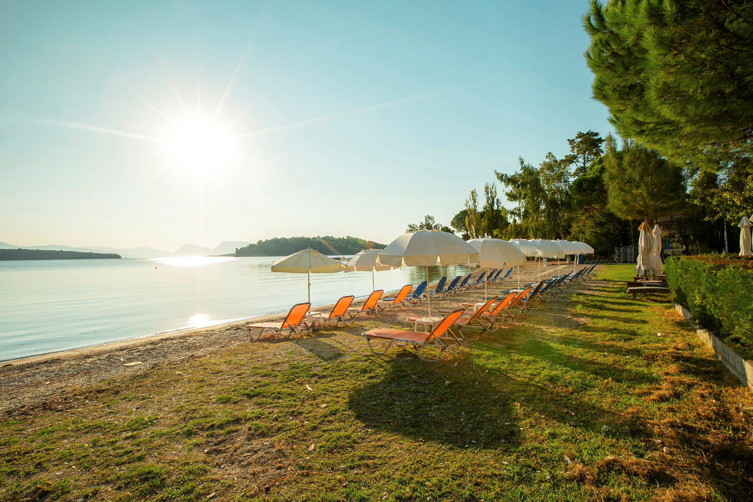 Strand med solsenger og parasoller ved soloppgang. (AI-generert tekst)