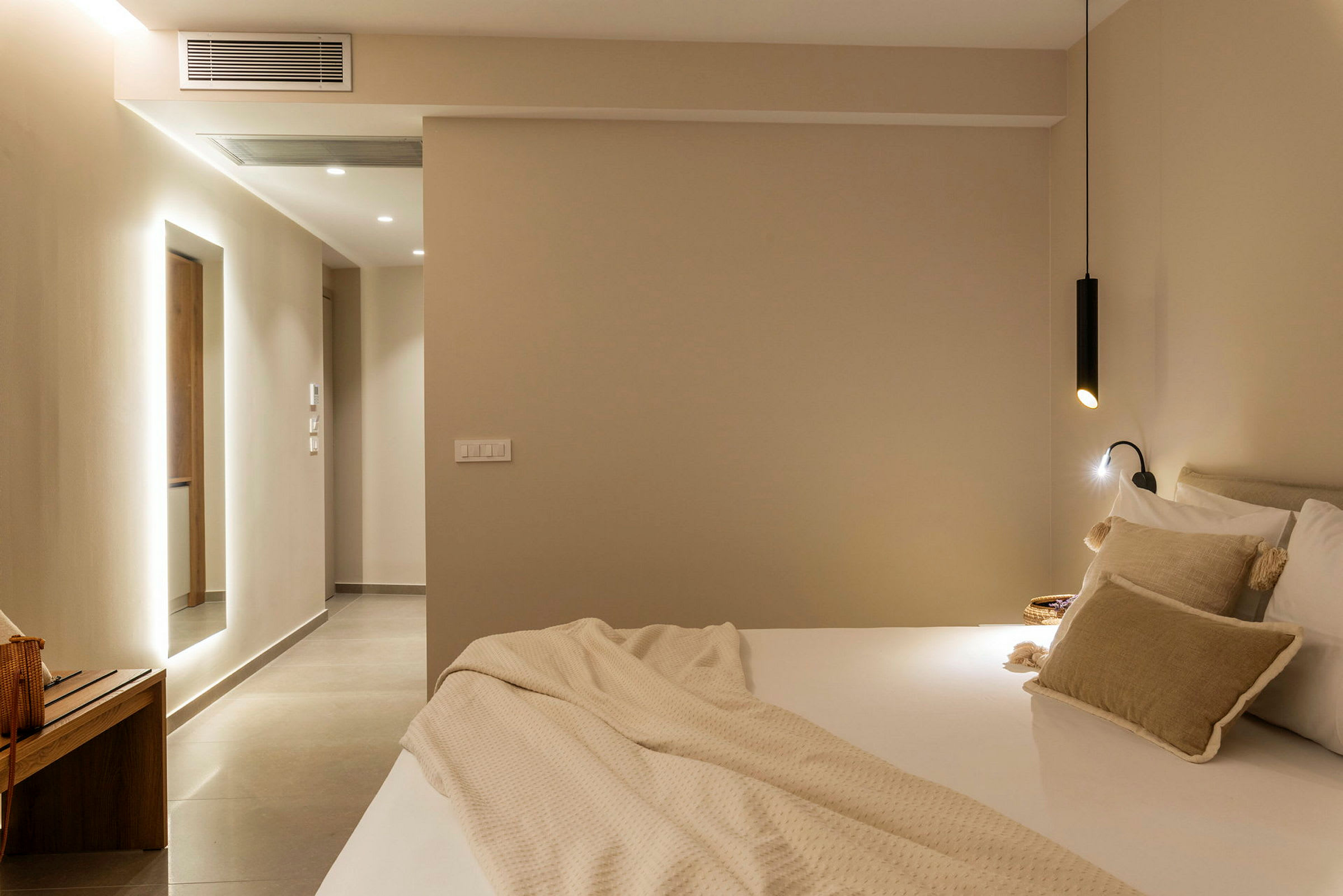 Et moderne hotellrom med seng og myke puter samt minimalistisk belysning. (AI-generert tekst)