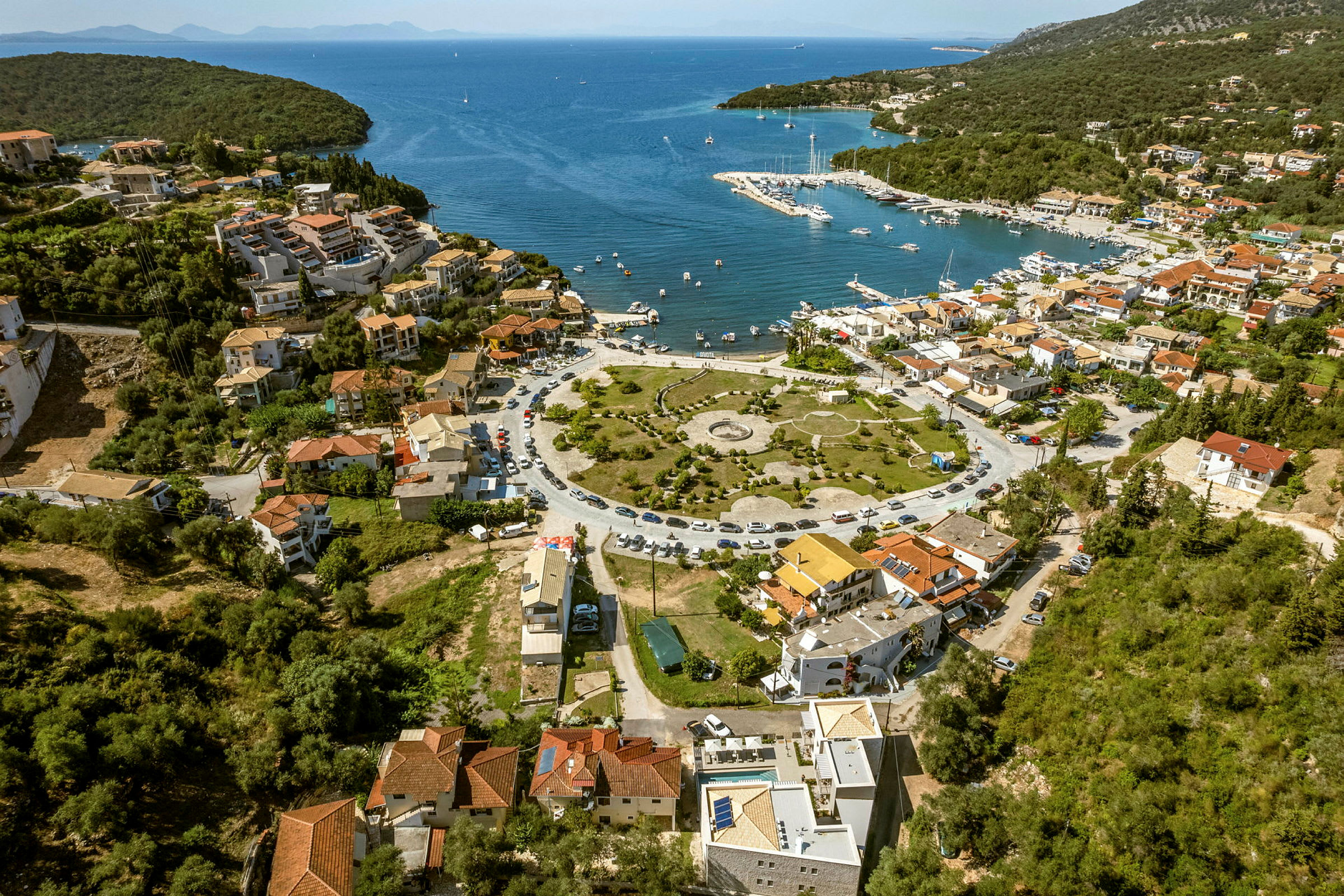 Luftutsikt over en kystby med en småbåthavn ved et blått hav. (AI-generert tekst)
