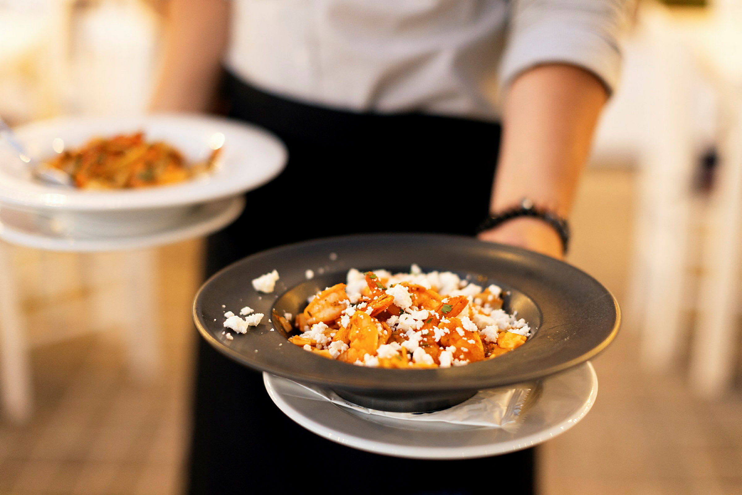 En person holder to tallerkener med pasta. (AI-generert tekst)