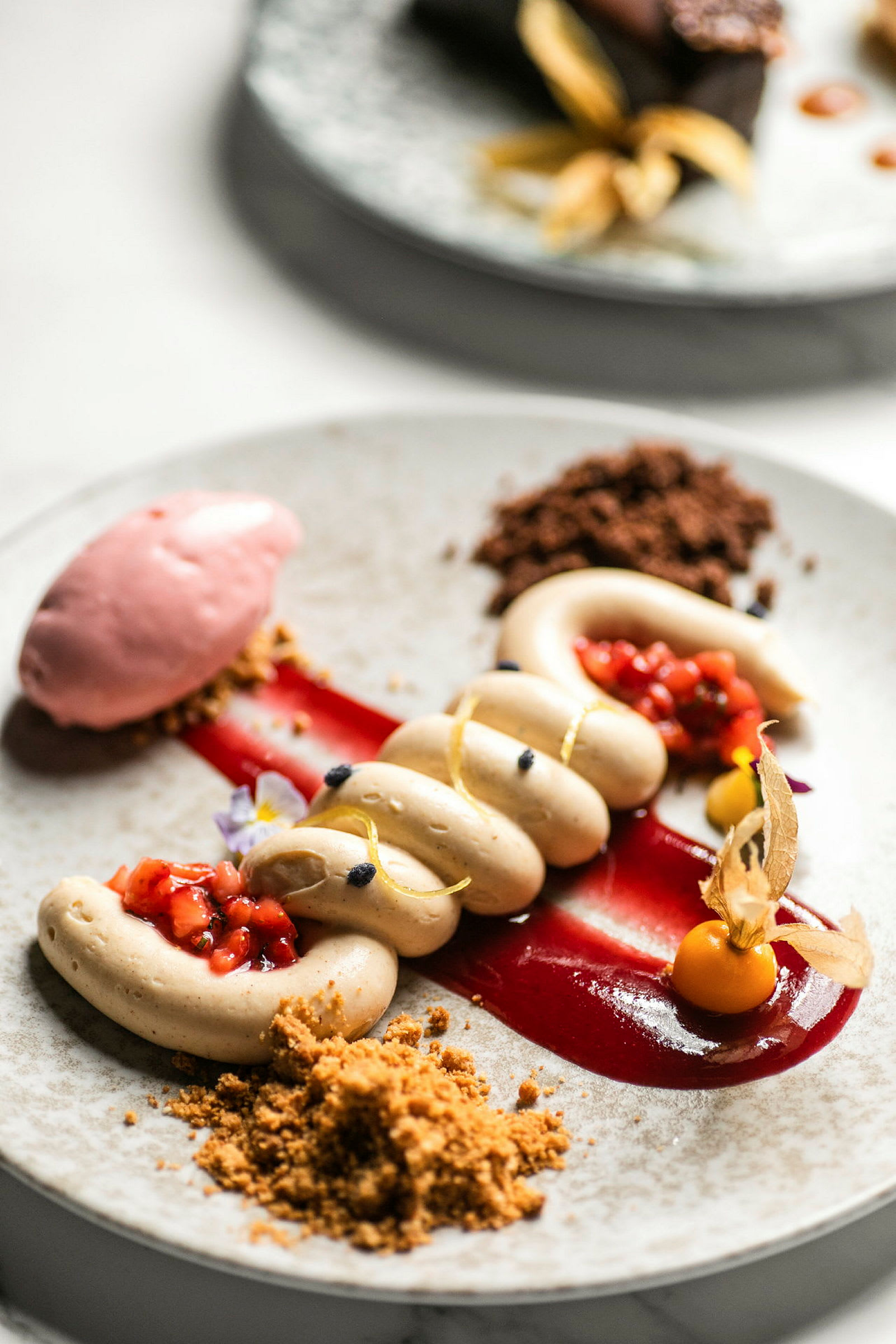 En tallerken med en elegant anrett dessert bestående av forskjellige kremete og fruktige komponenter. (AI-generert tekst)