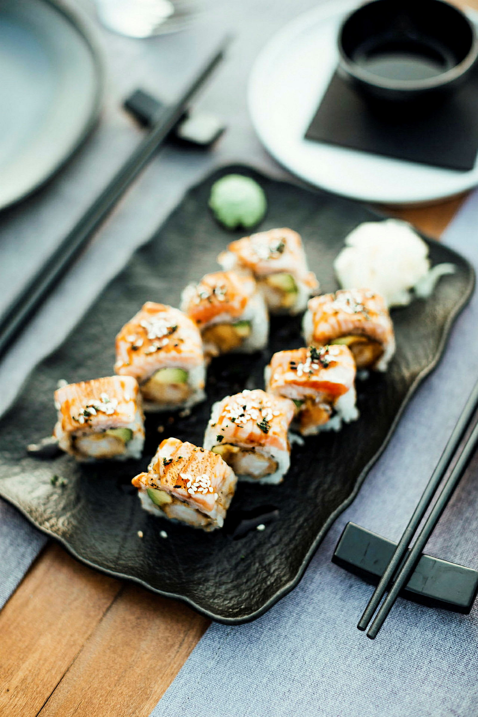 Retten viser en servering av sushi anrettet på et svart fat med dekorasjoner. (AI-generert tekst)