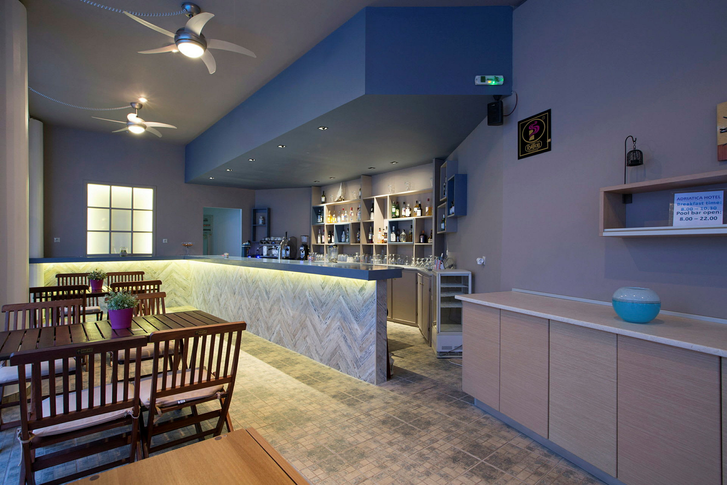 En interiørvisning av en hotellbar med trebord og stoler samt en opplyst bar. (AI-generert tekst)