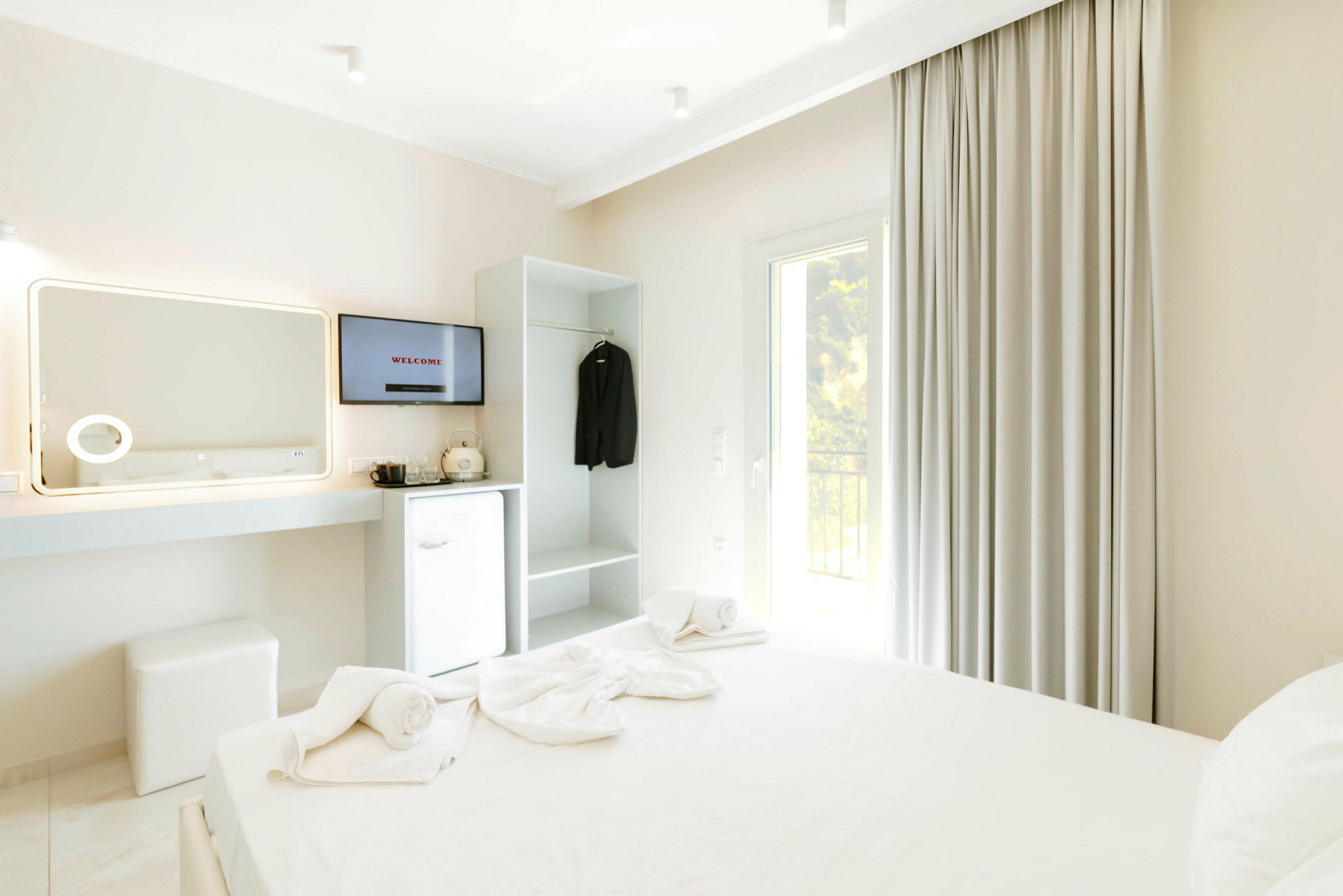 Et hotellrom med en oppredd seng, TV, kjøleskap og garderobe. (AI-generert tekst)