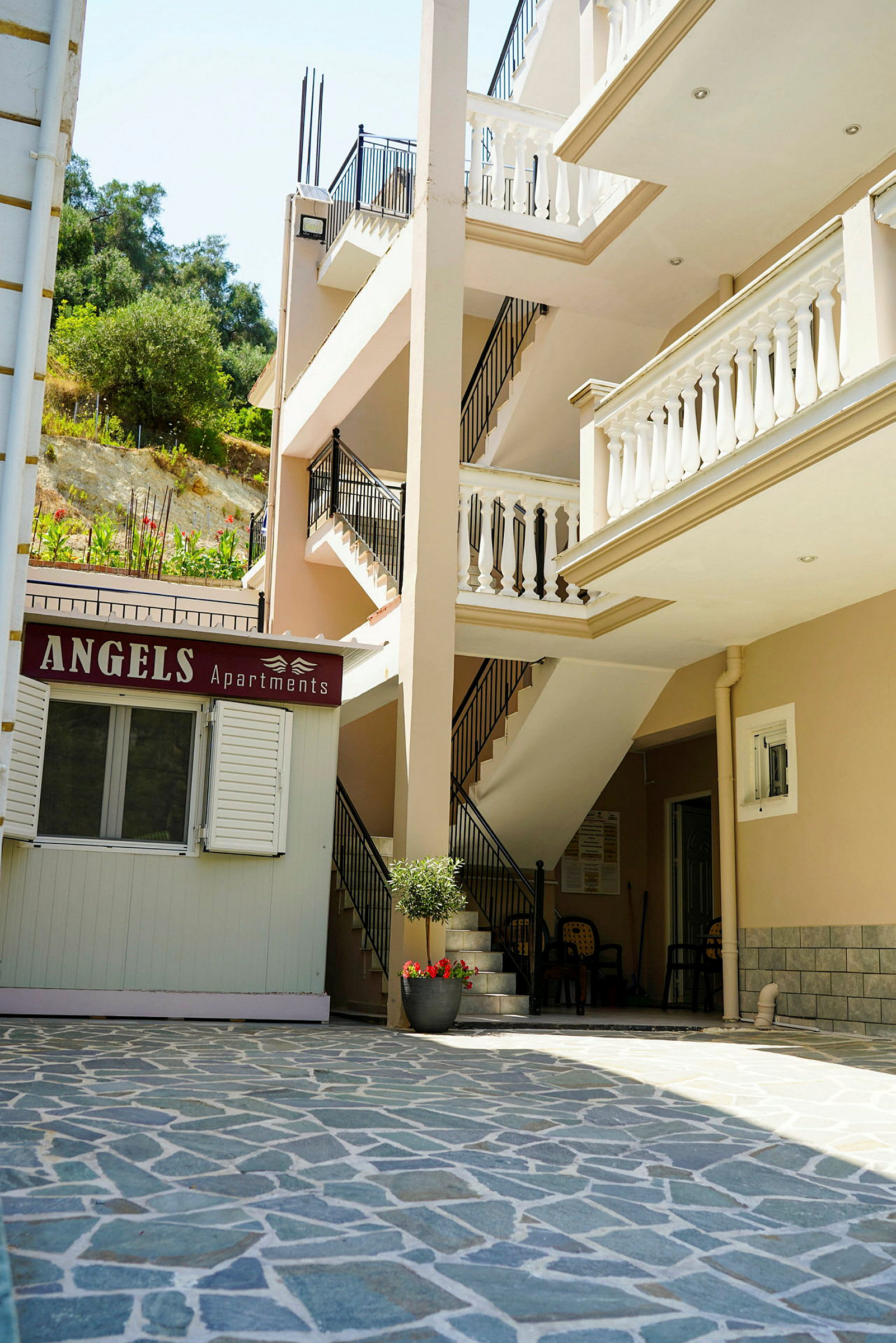Bilde av en bygning med balkonger og et skilt med teksten 'Angels Apartments'. (AI-generert tekst)