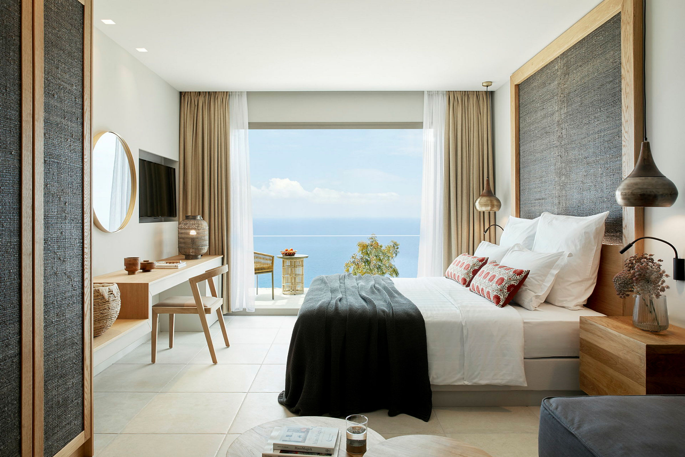 Moderne innredet hotellrom med havutsikt fra en stor glassdør. (AI-generert tekst)