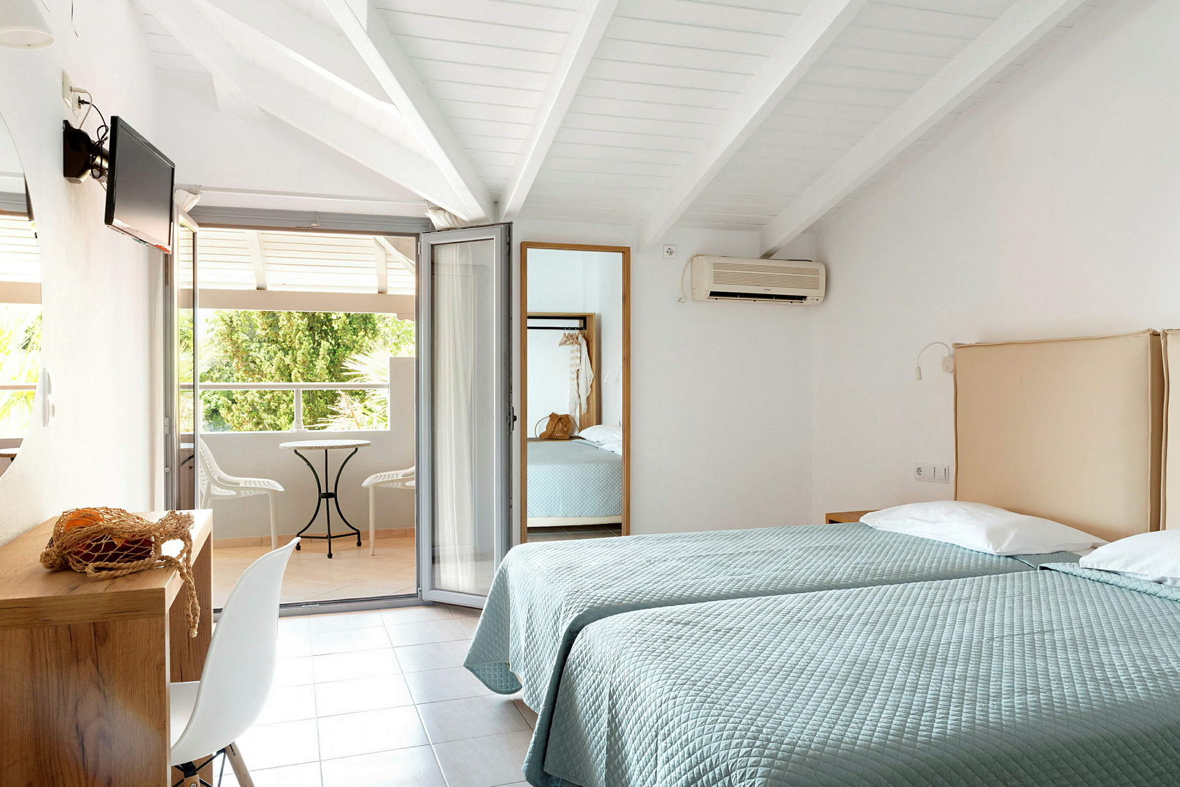 To enkeltsenger i et hotellrom med åpning mot en møblert balkong. (AI-generert tekst)