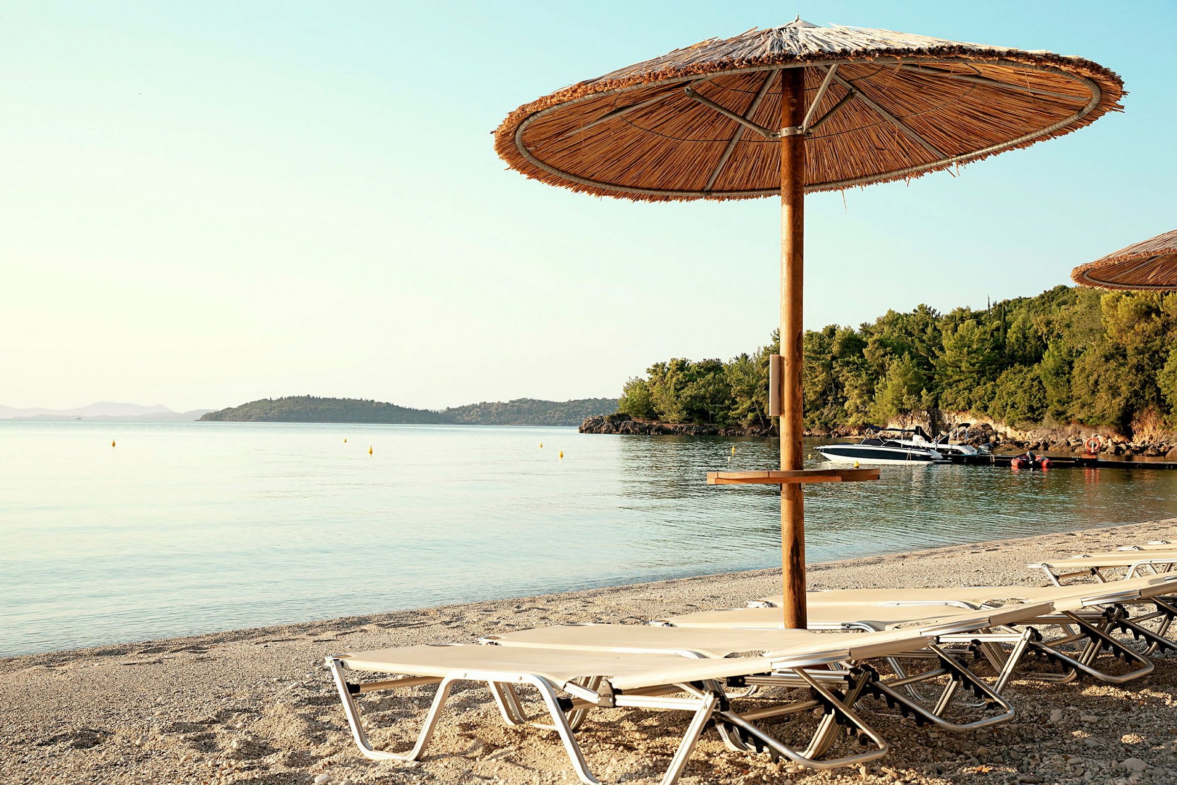 Strand med solsenger og parasoll ved vannkanten. (AI-generert tekst)