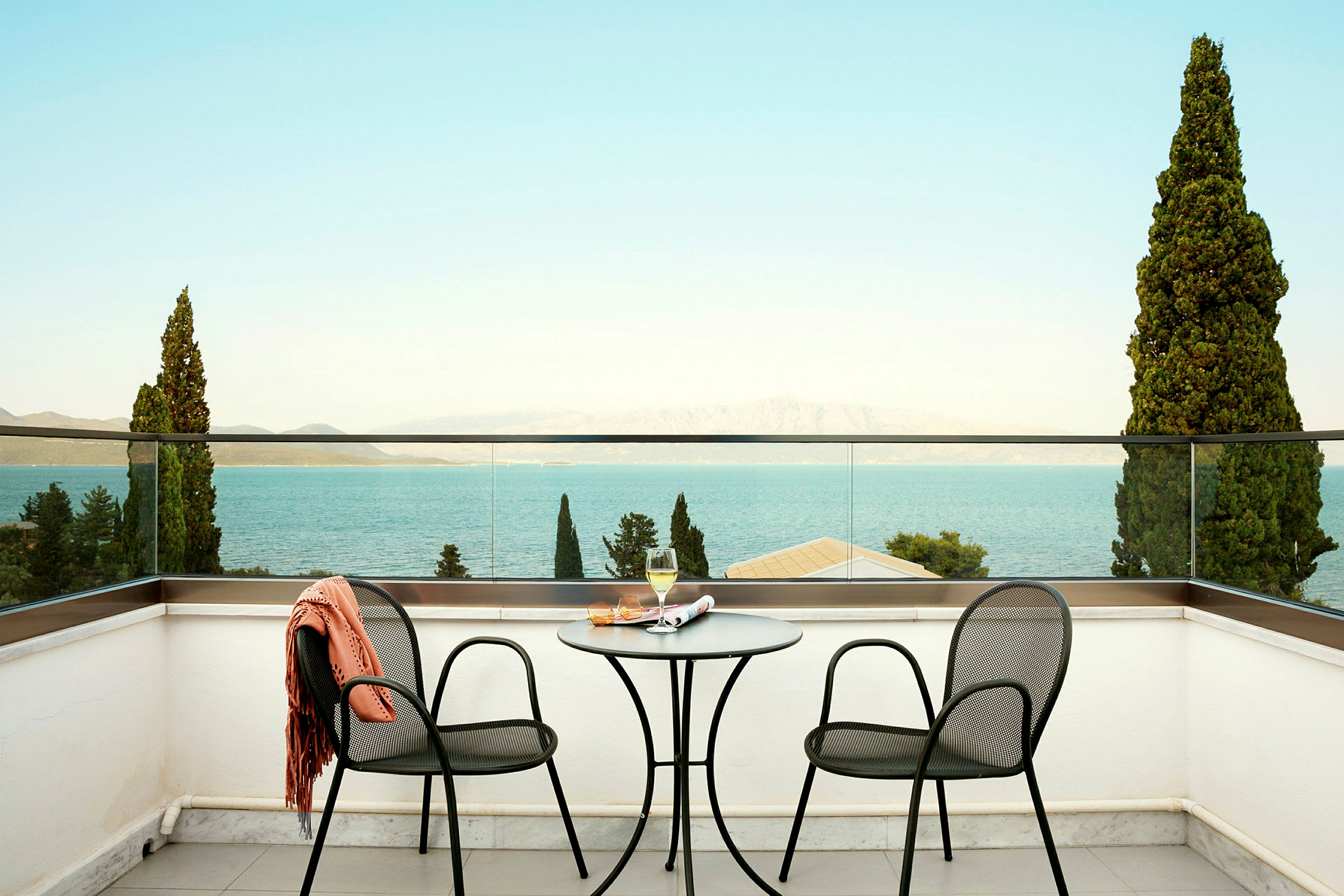 To stoler og et bord på en terrasse med utsikt mot havet. (AI-generert tekst)
