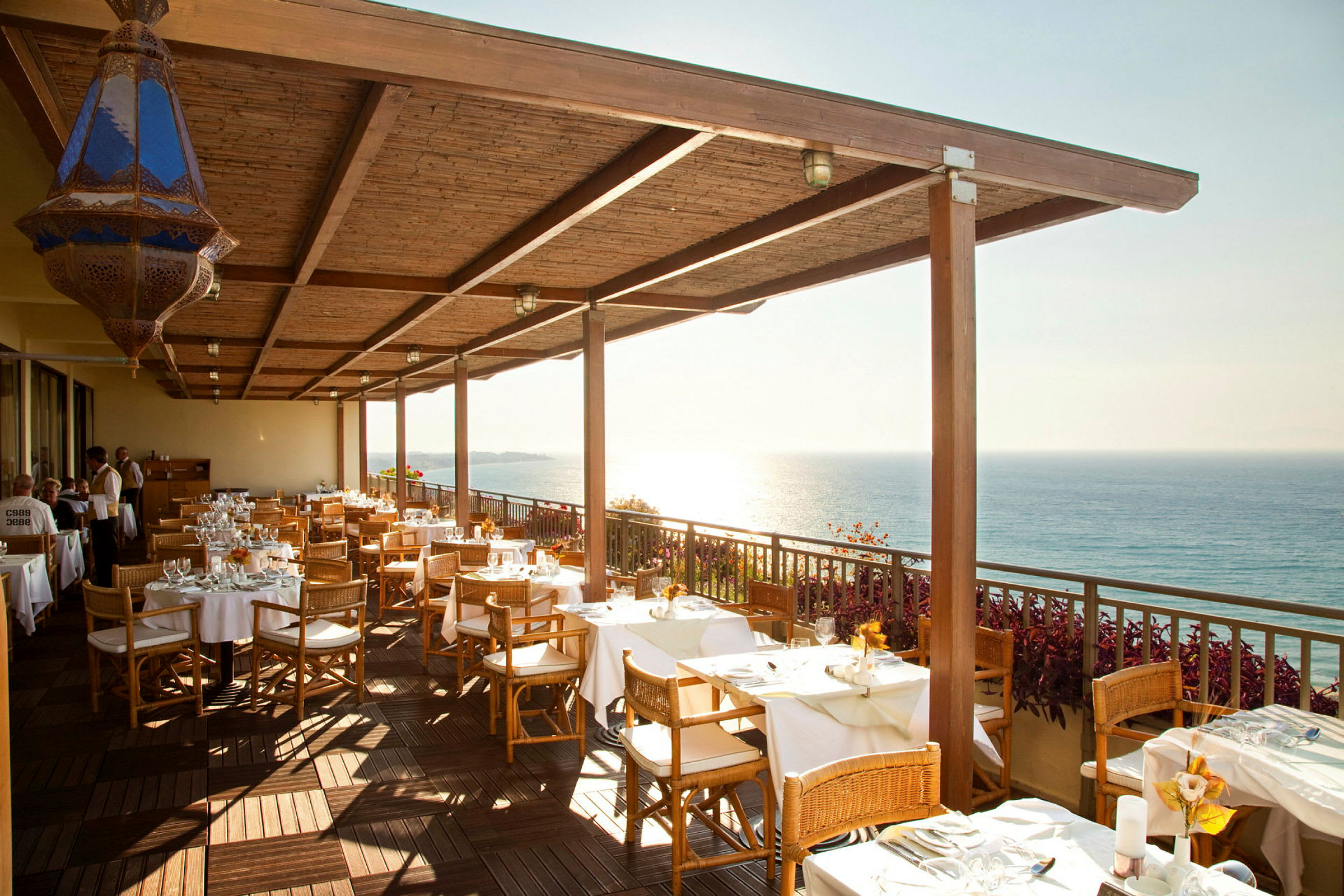 Restaurantterrasse med dekkede bord og havutsikt. (AI-generert tekst)