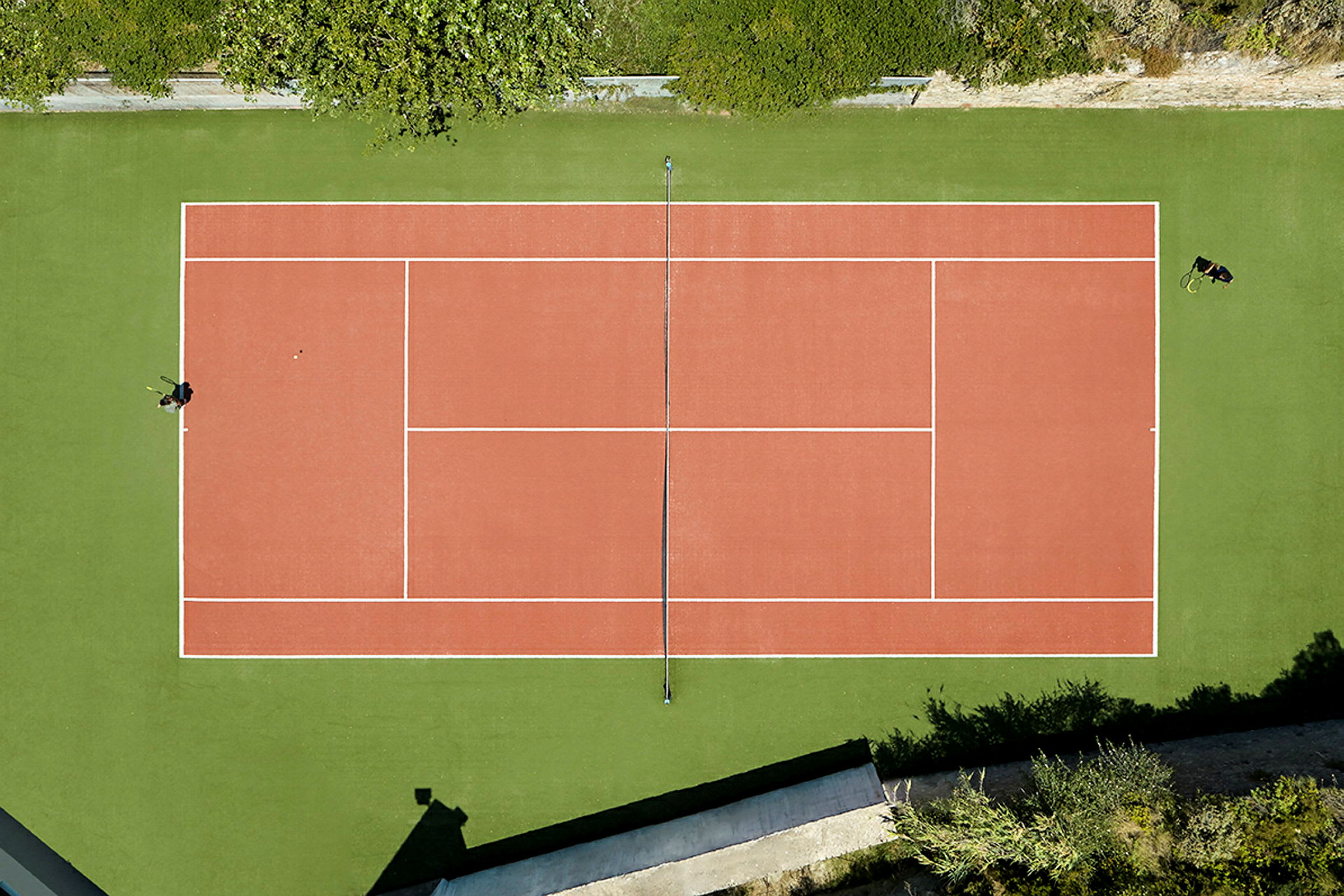 En tennisbane sett ovenfra med grønn omgivelse. (AI-generert tekst)