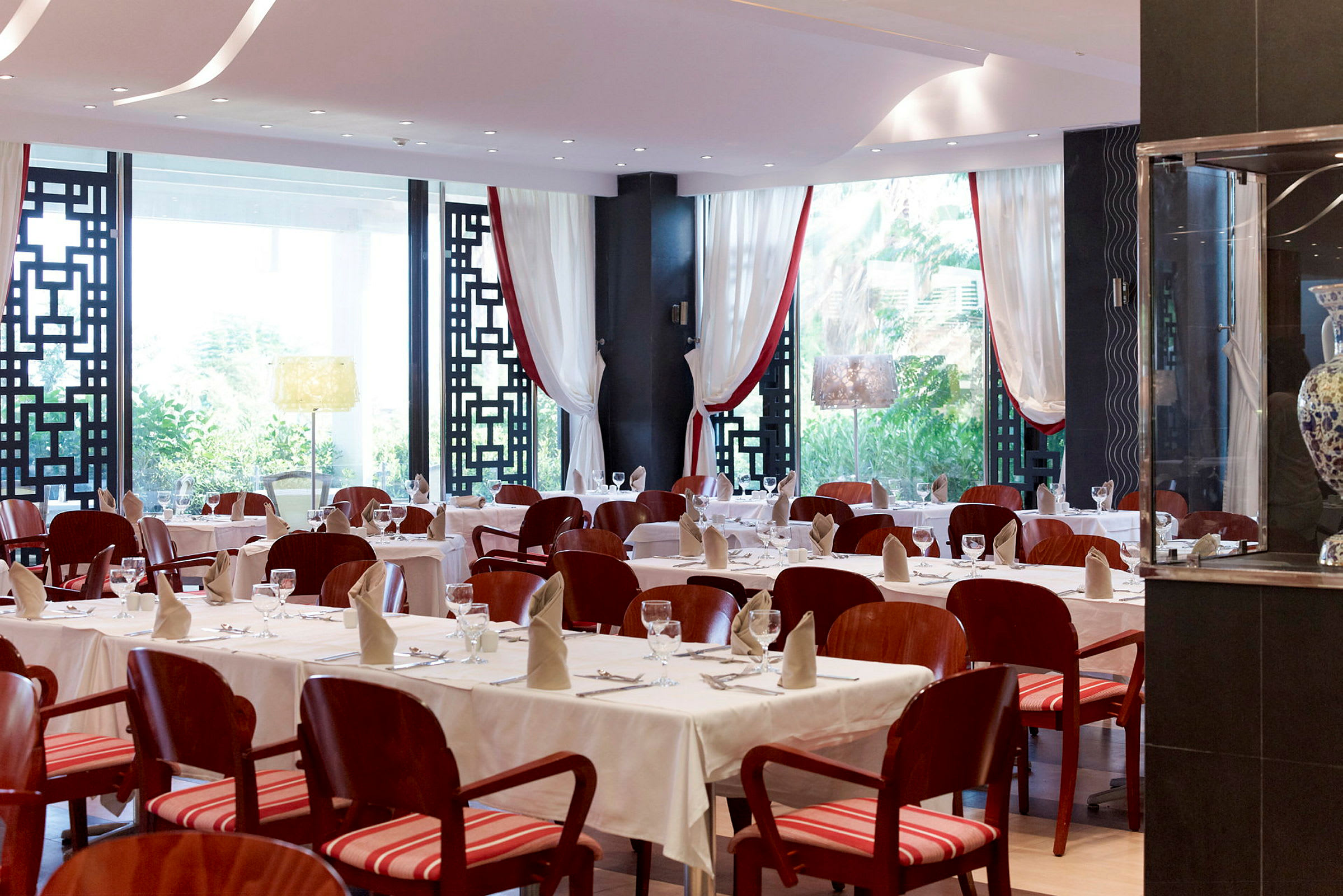 En elegant restaurant med dekte bord og røde stoler. (AI-generert tekst)