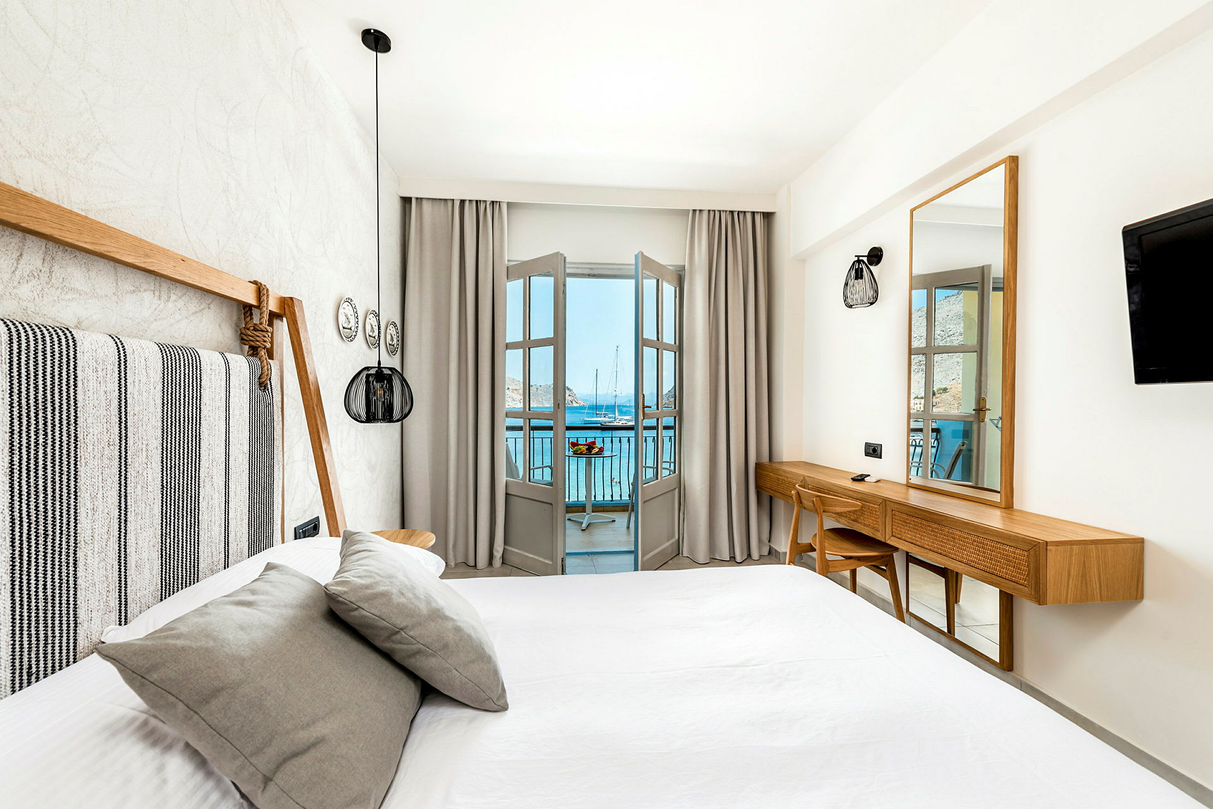 Et lyst og moderne innredet hotellrom med seng og utsikt mot havet fra en balkong. (AI-generert tekst)